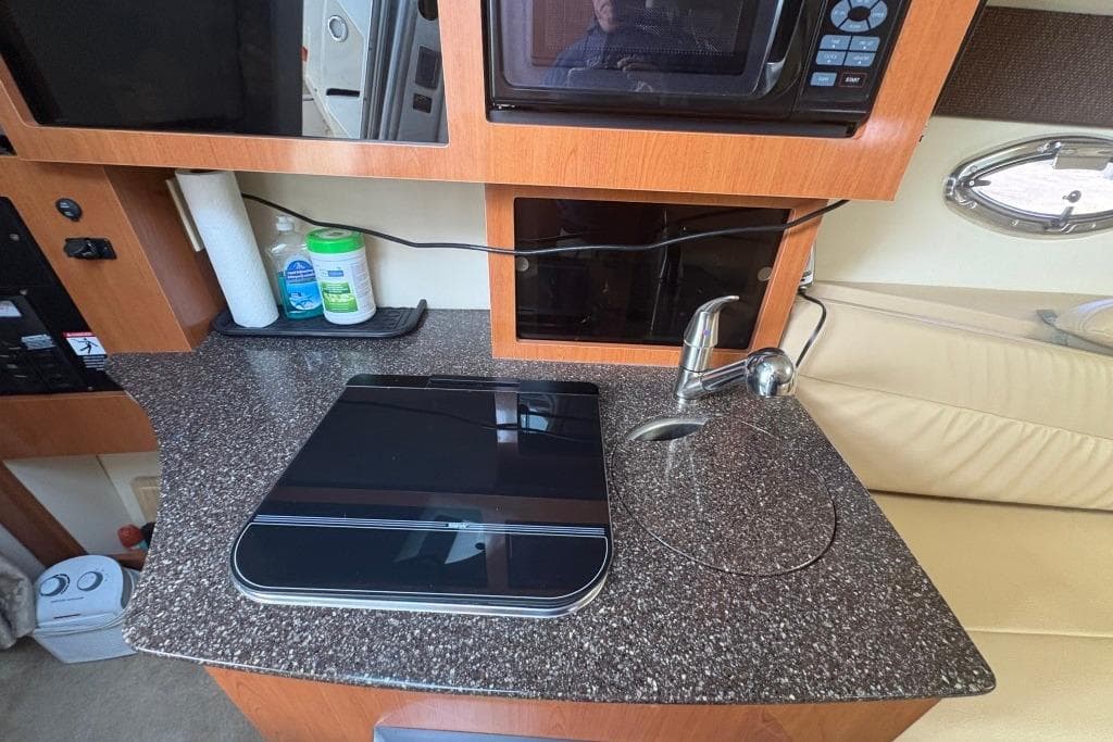 2008 Maxum 2700 SE boat interior with kitchenette, featuring sink, stove, and microwave.