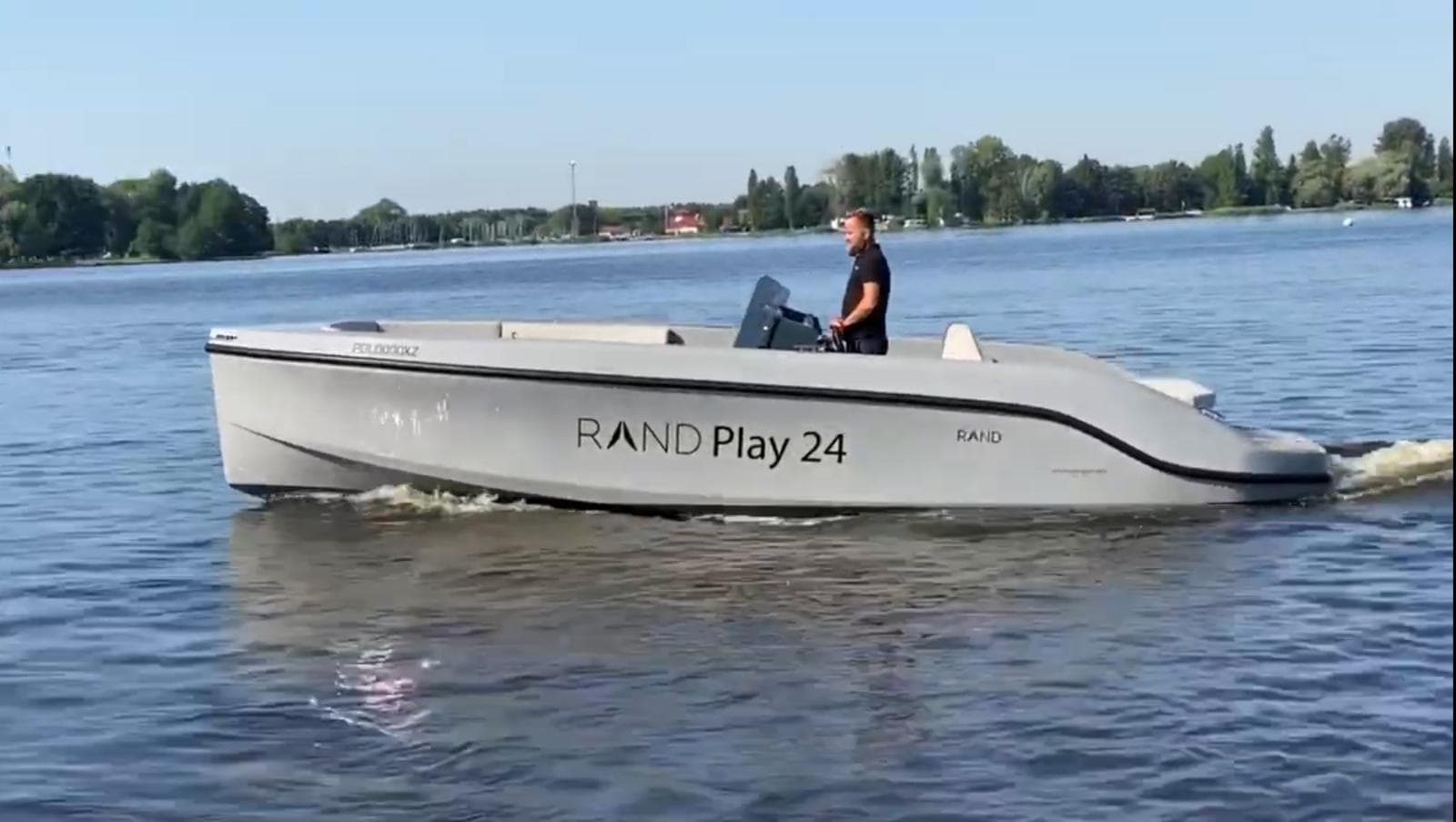 2022 Rand PLAY 24 boat cruising on a calm lake with a person steering.