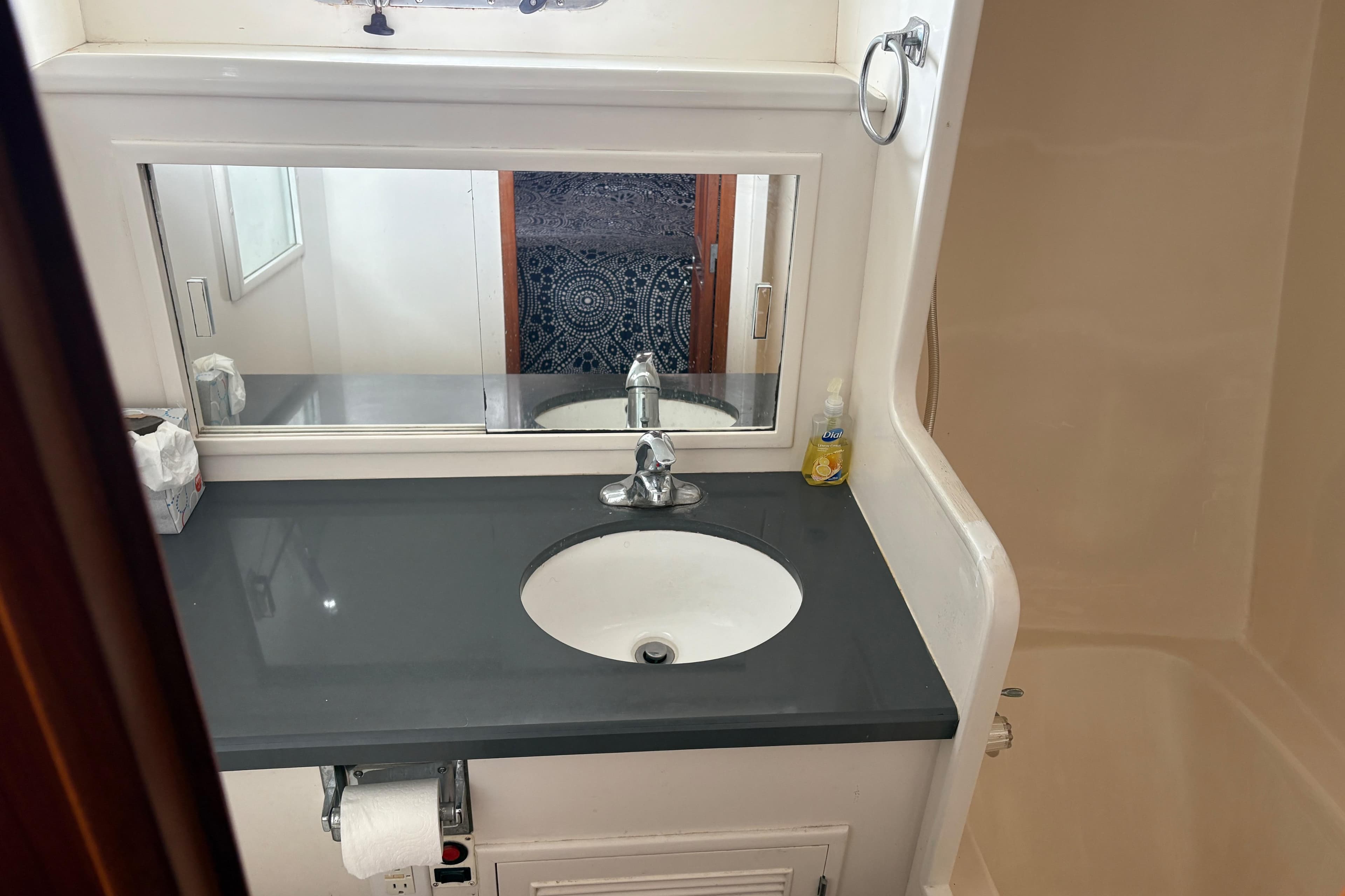 Bathroom sink area in a 1990 Angel Pilothouse boat, featuring a mirror and countertop.