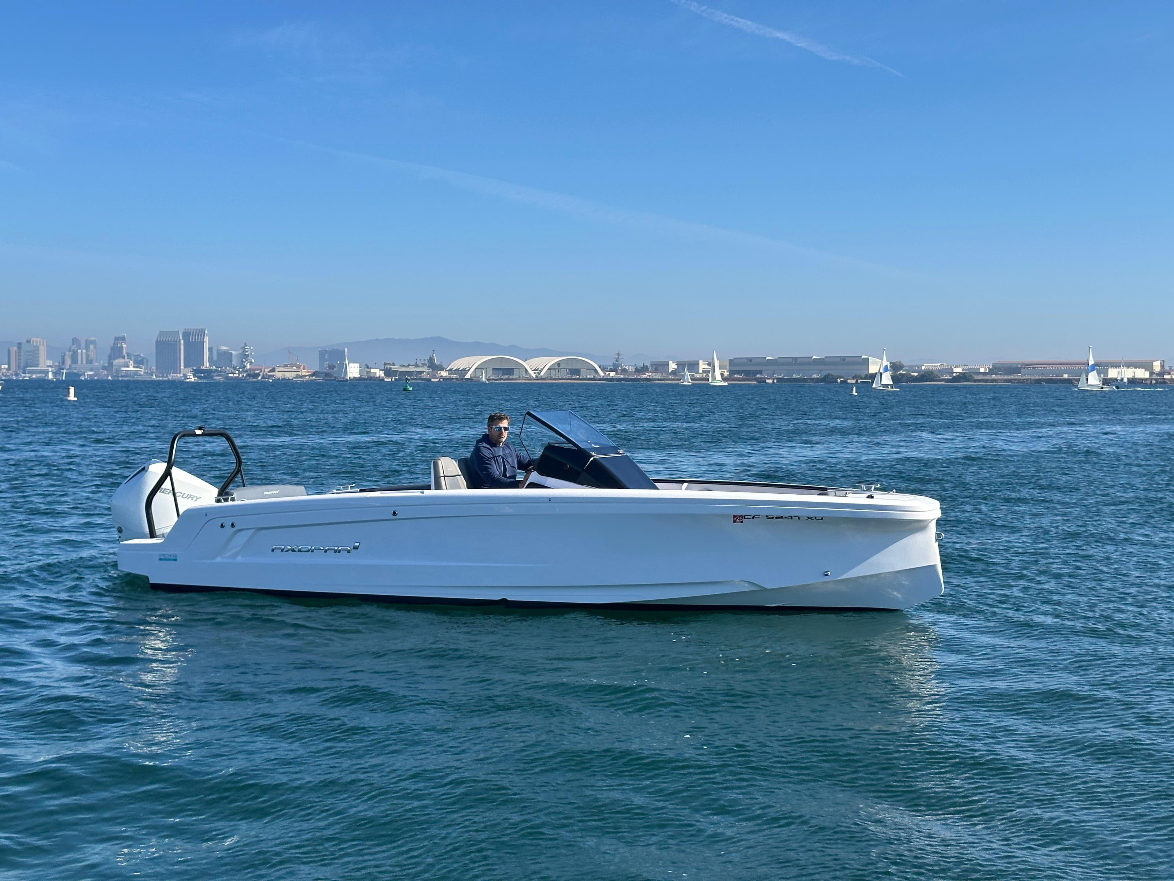 2021 Axopar 22 Spyder boat cruising on a sunny day with city skyline in background.