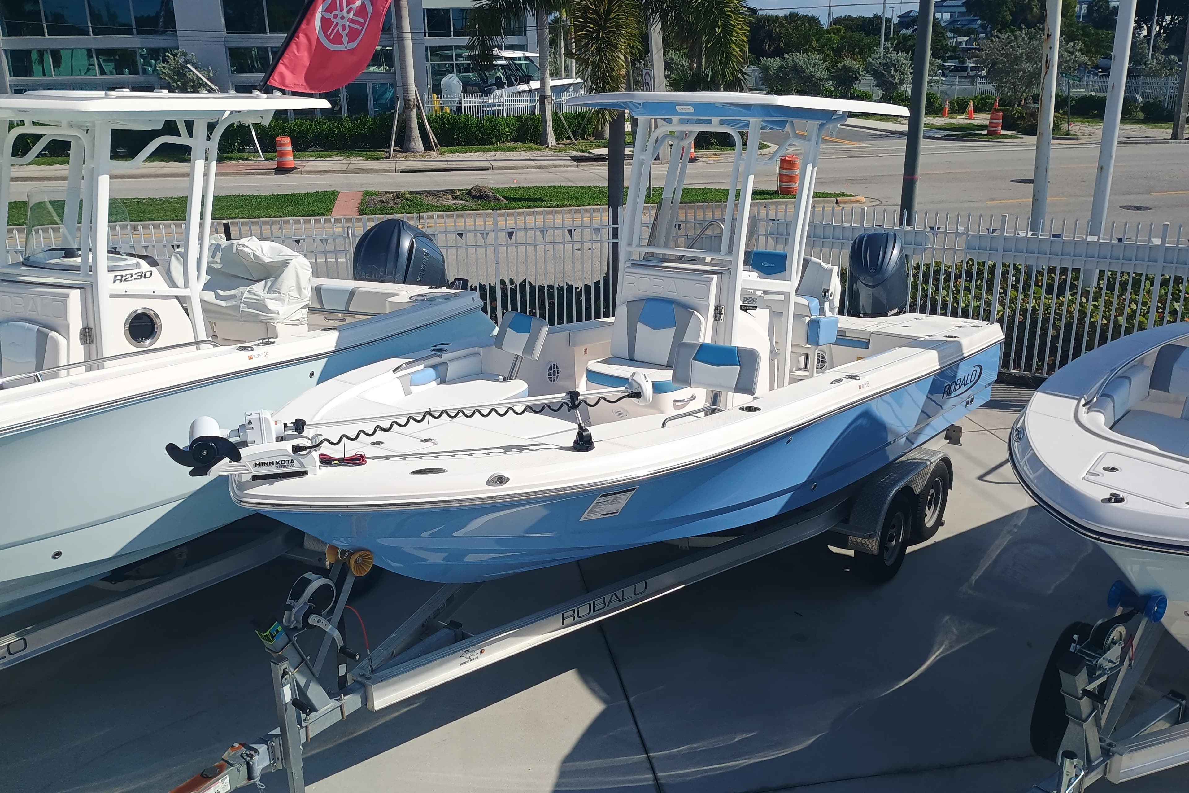 2026 Robalo 226 Cayman boat on trailer, blue and white design, parked outdoors.