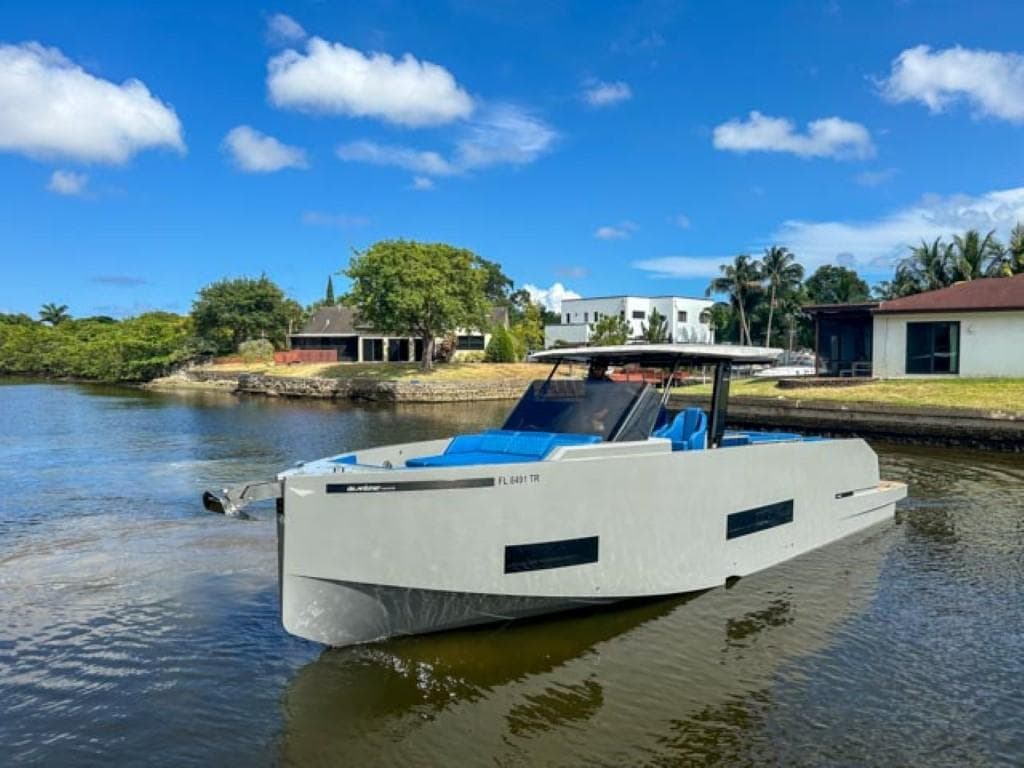 2023 De Antonio Yachts D42 Open cruising on a sunny day near waterfront homes.