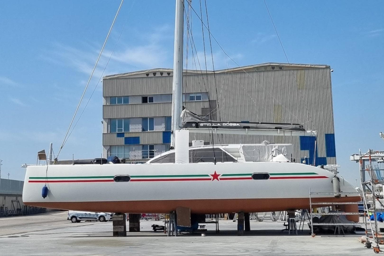 2017 Ice Yachts Ice Cat 61 catamaran on dry dock, with industrial building backdrop.