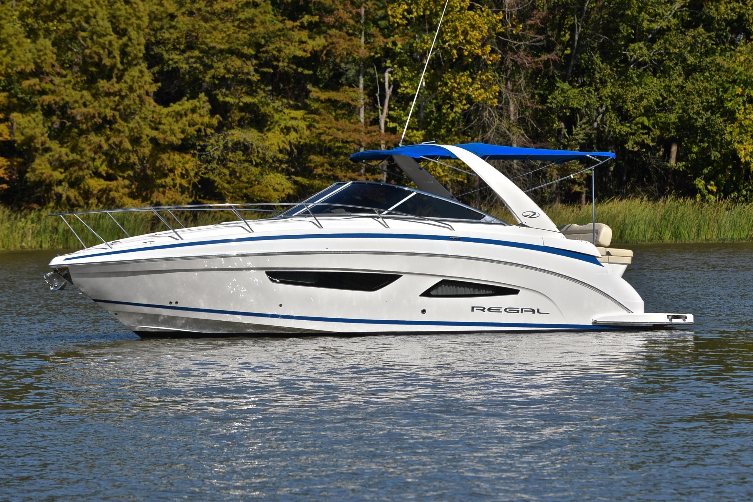2018 Regal 33 Express boat cruising on a serene lake with lush green trees.