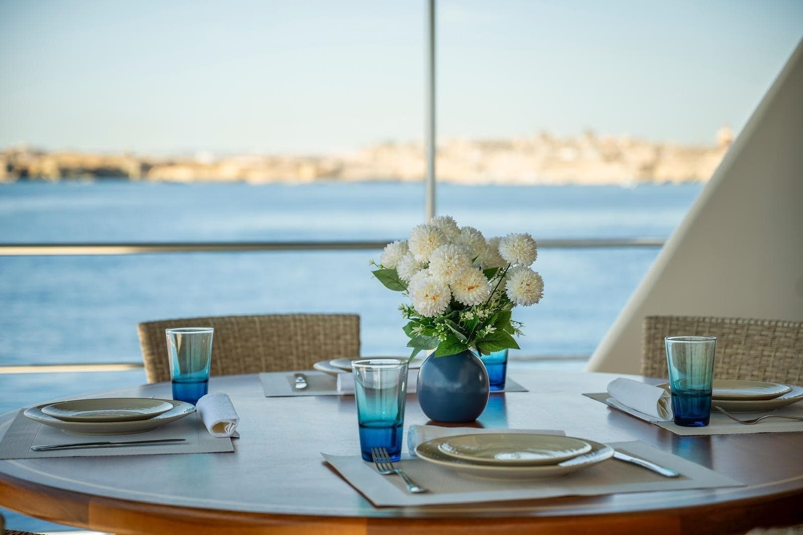 Elegant yacht dining setup with flowers, overlooking serene ocean view.