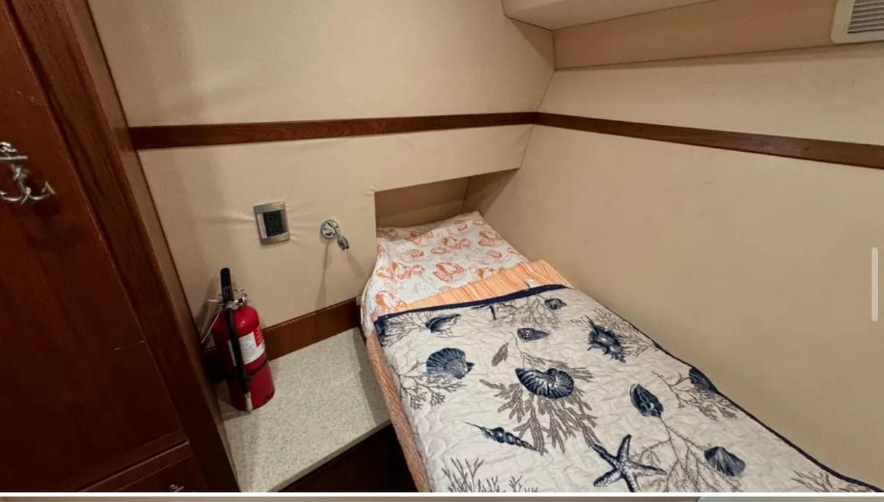 1987 Blackfin Convertible cabin with single bed, nautical-themed bedding, and fire extinguisher.