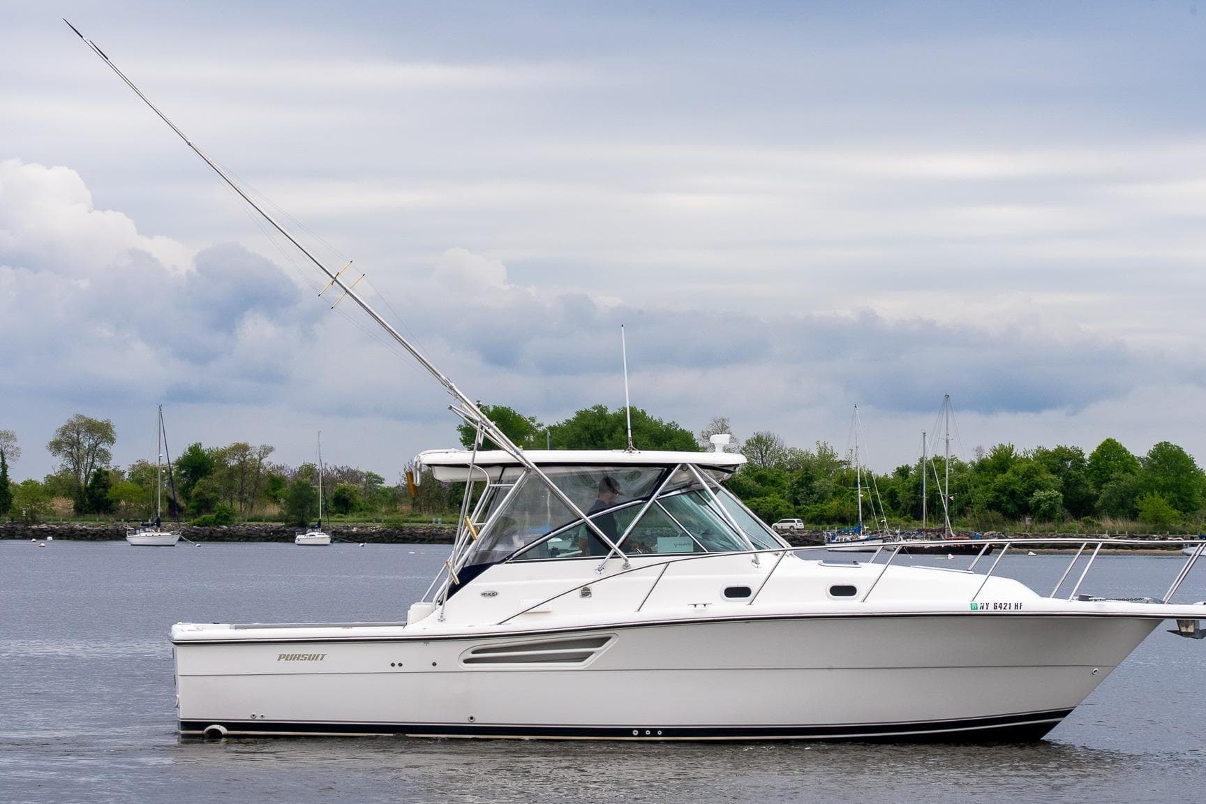 2003 Pursuit 3400 Express boat on calm water with cloudy sky background.