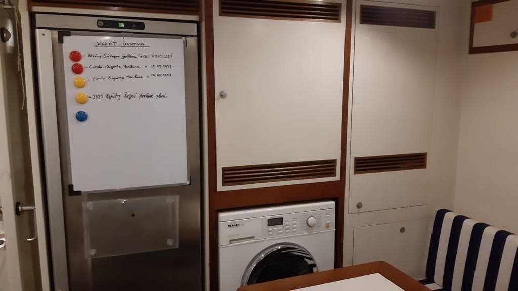 Interior of yacht kitchen with washing machine and refrigerator.