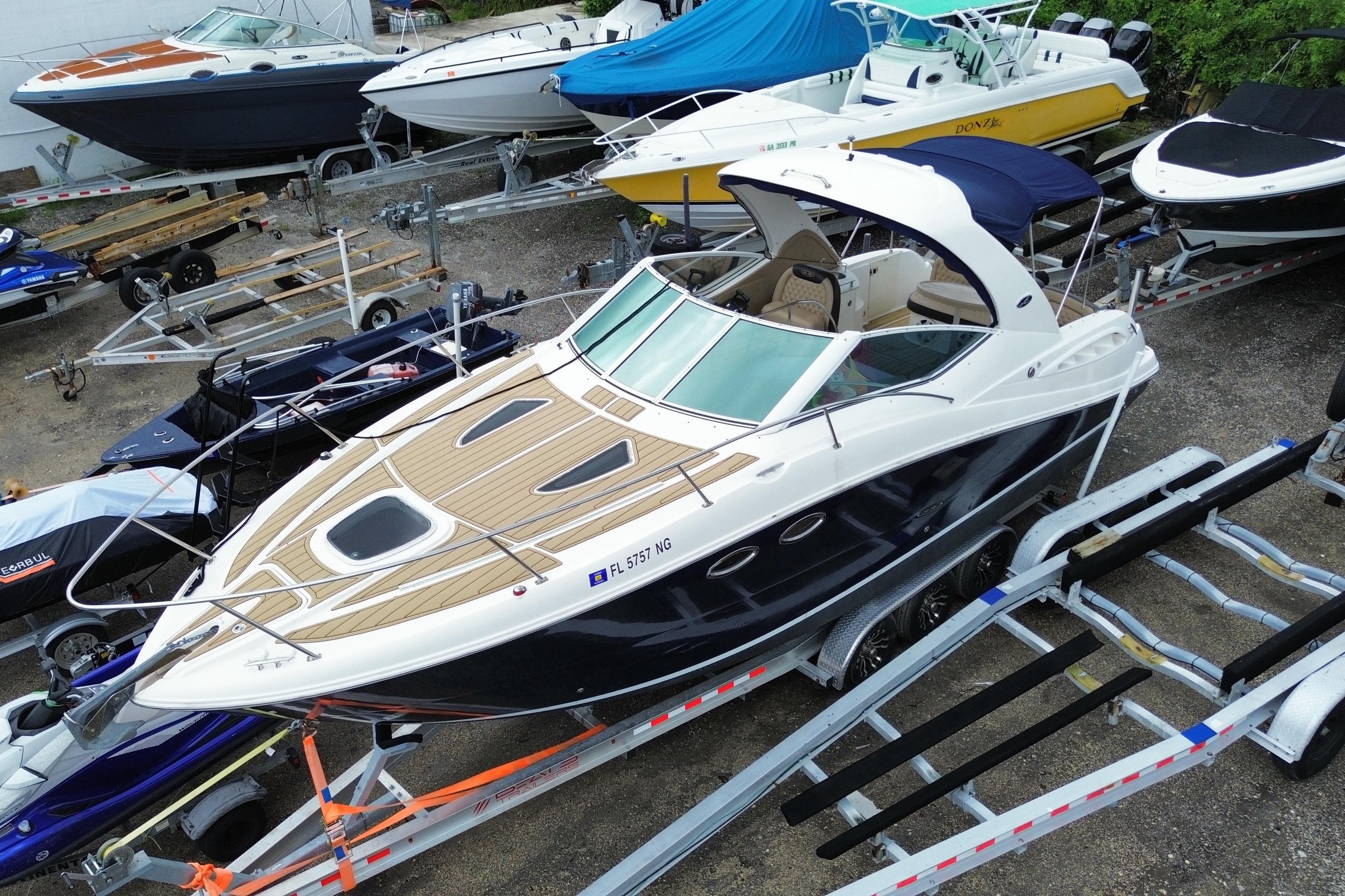 2006 Sea Ray 290 Sundancer boat on trailer, surrounded by other boats in storage yard.