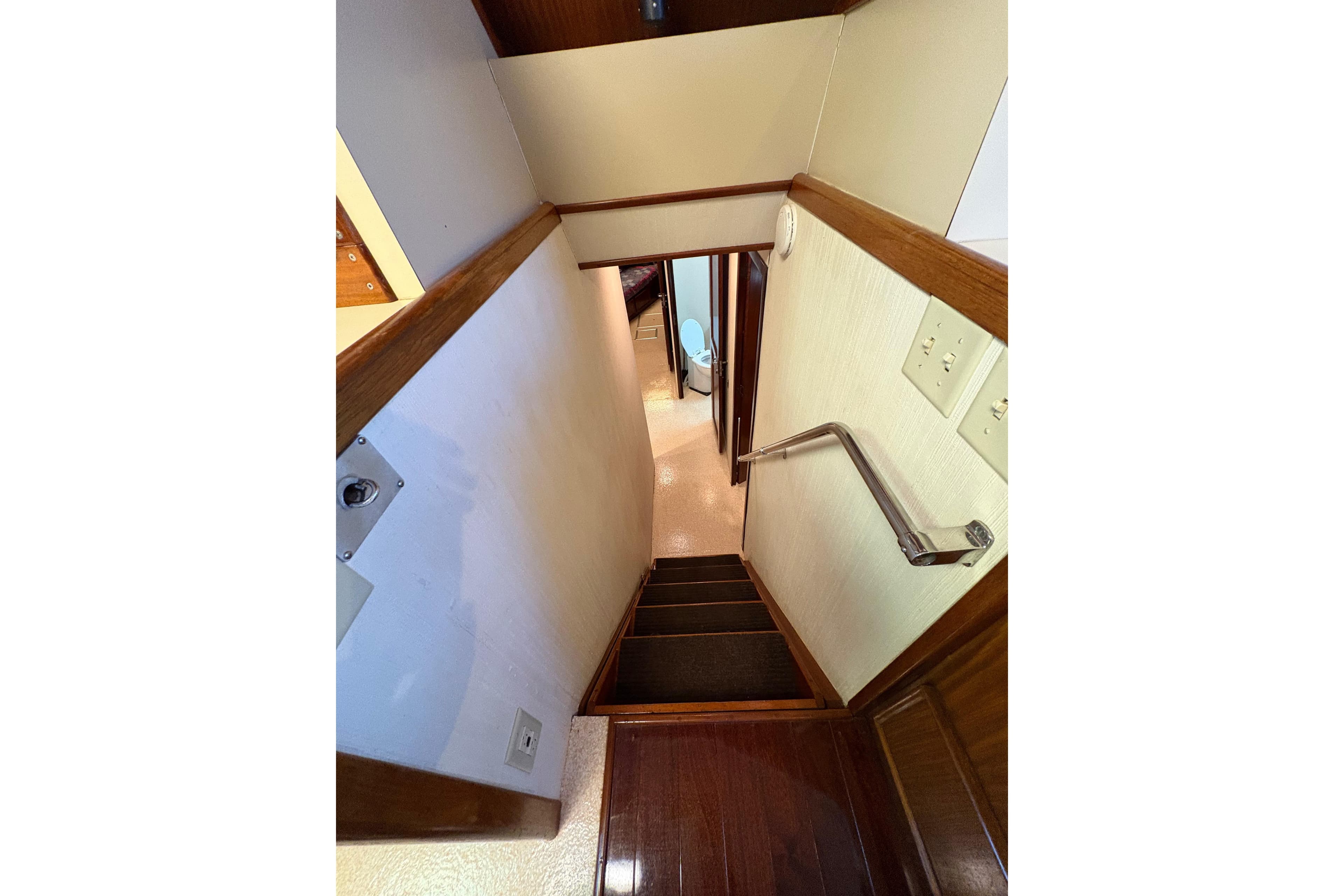 Interior staircase of 1985 Hatteras 60 Convertible yacht, featuring wooden steps and handrail.