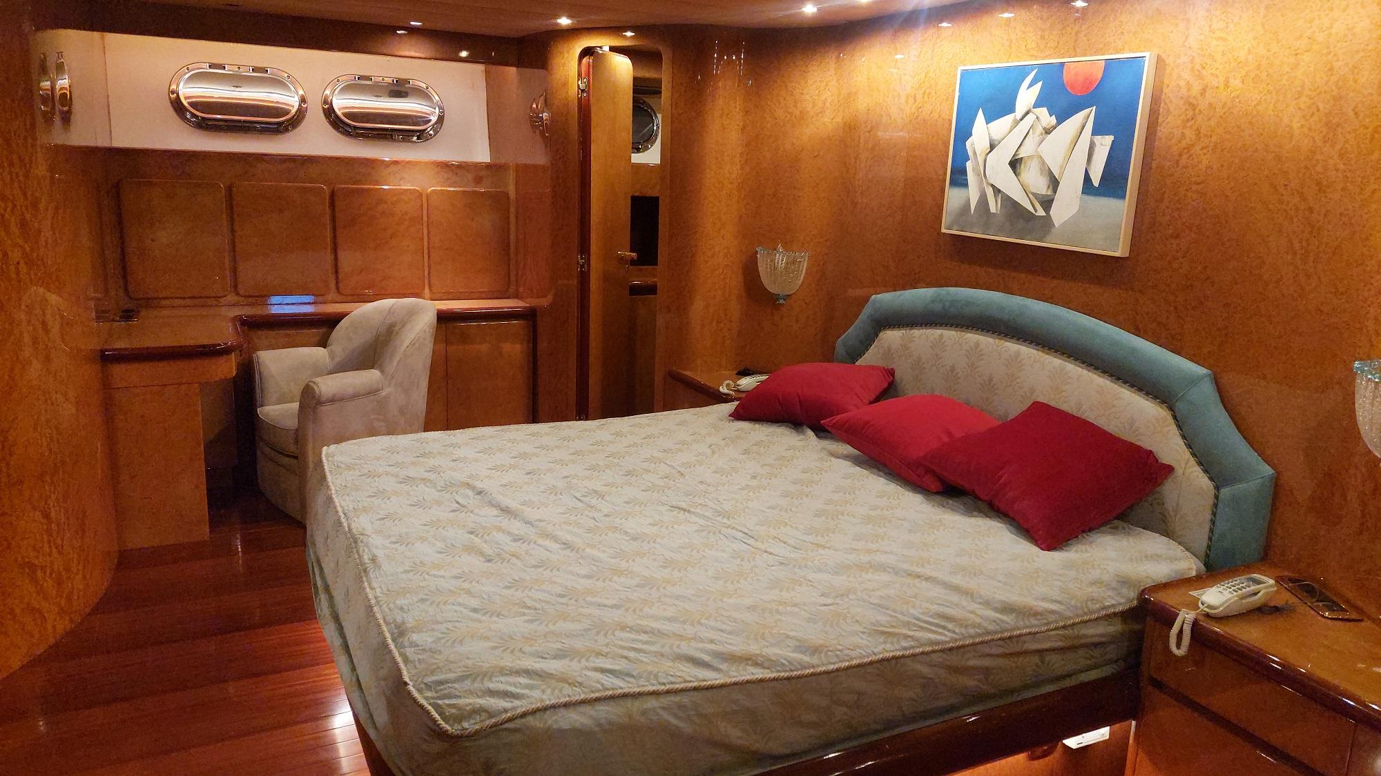 Luxurious yacht bedroom with modern decor, featuring a bed, artwork, and wooden furnishings. Admiral 28, 1992.