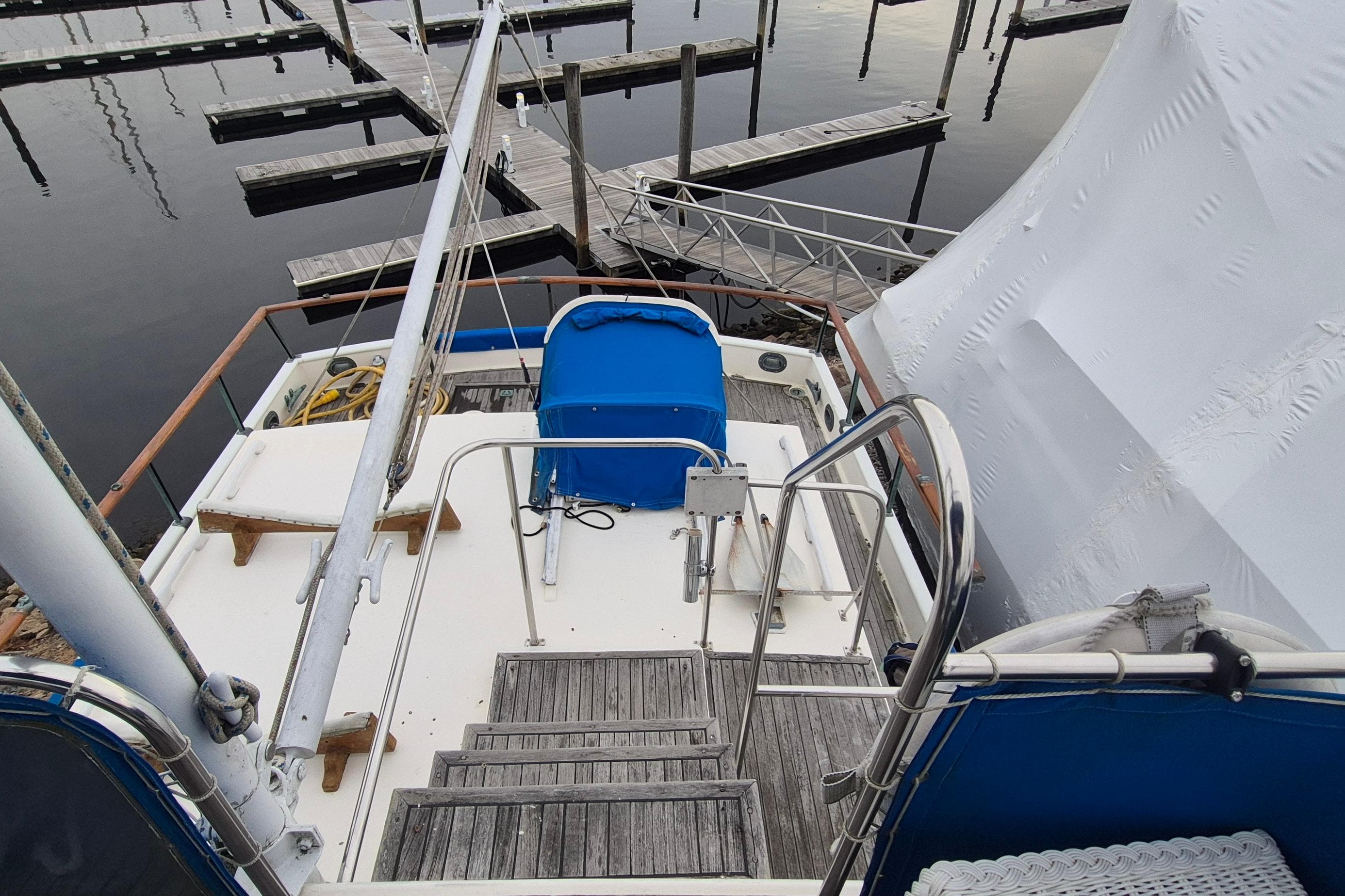 1983 Grand Banks 42 Classic yacht deck with blue cover, docked at marina.