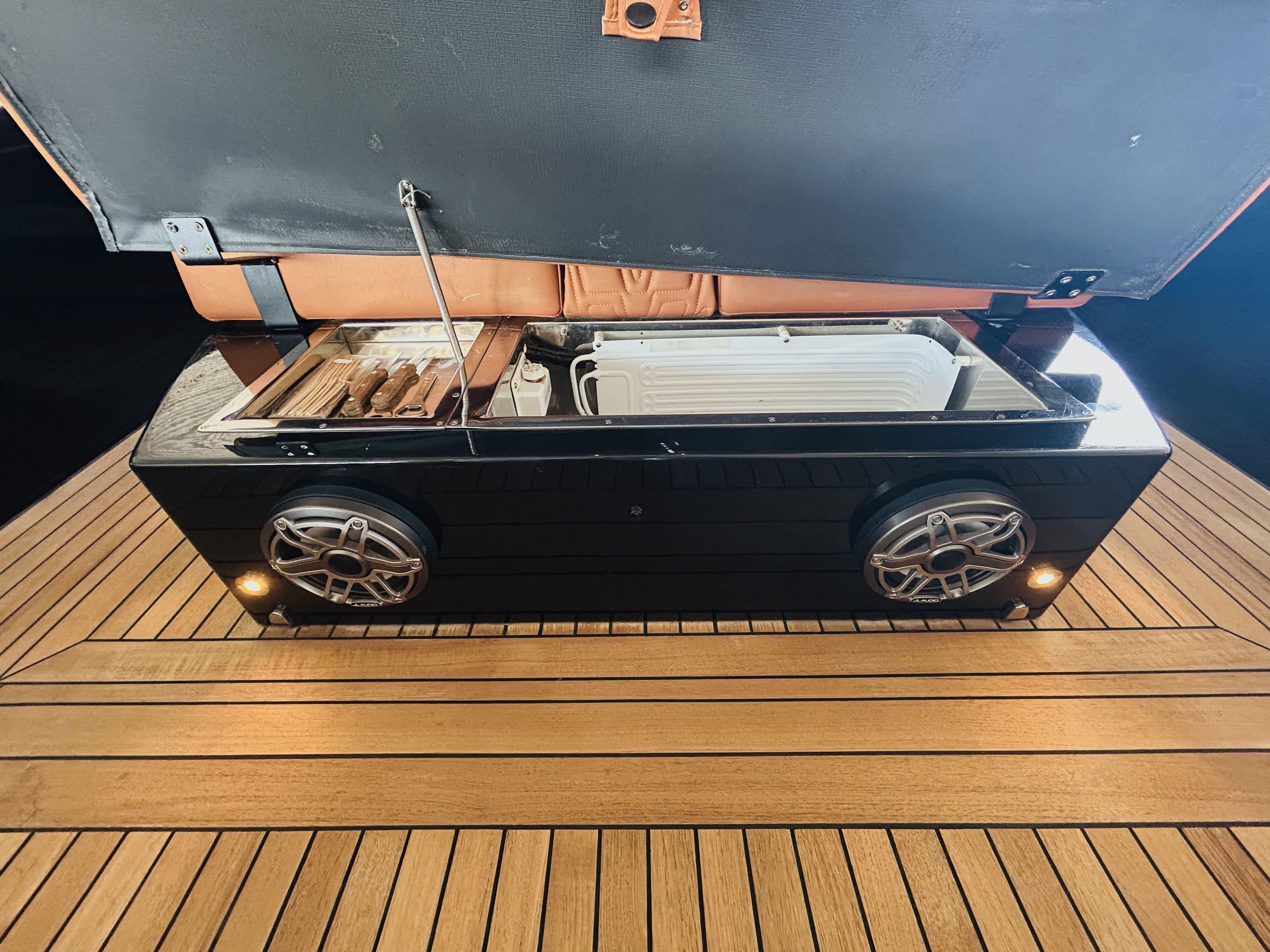 Open storage compartment on Technohull Omega 47 yacht, featuring speakers and wooden deck, 2021 model.