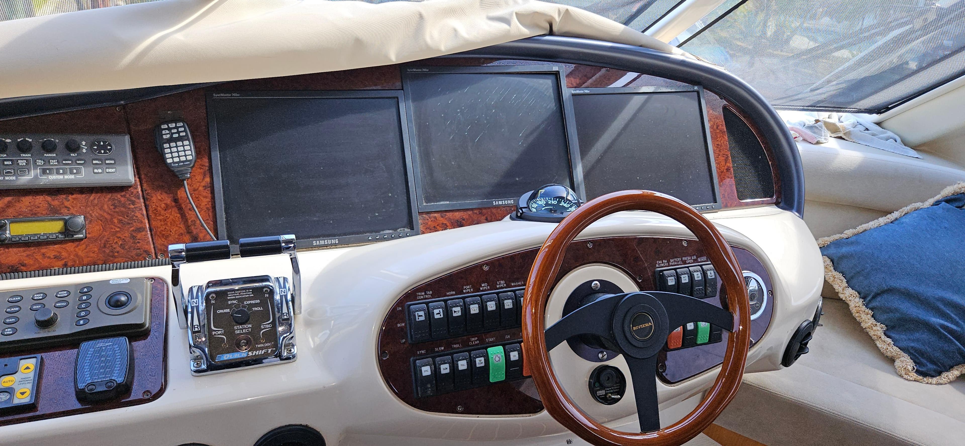 2004 Riviera 58 Enclosed Flybridge helm with wood steering wheel and multiple control panels.