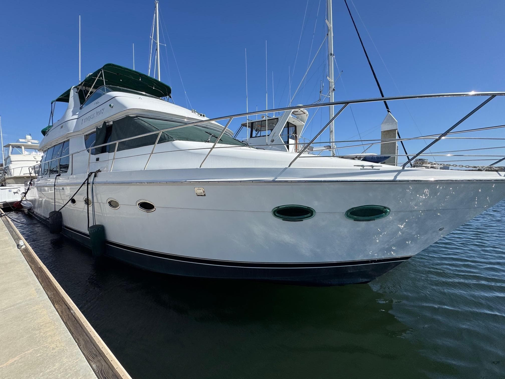 2002 Carver 570 Voyager Pilothouse yacht docked in marina under clear blue sky.