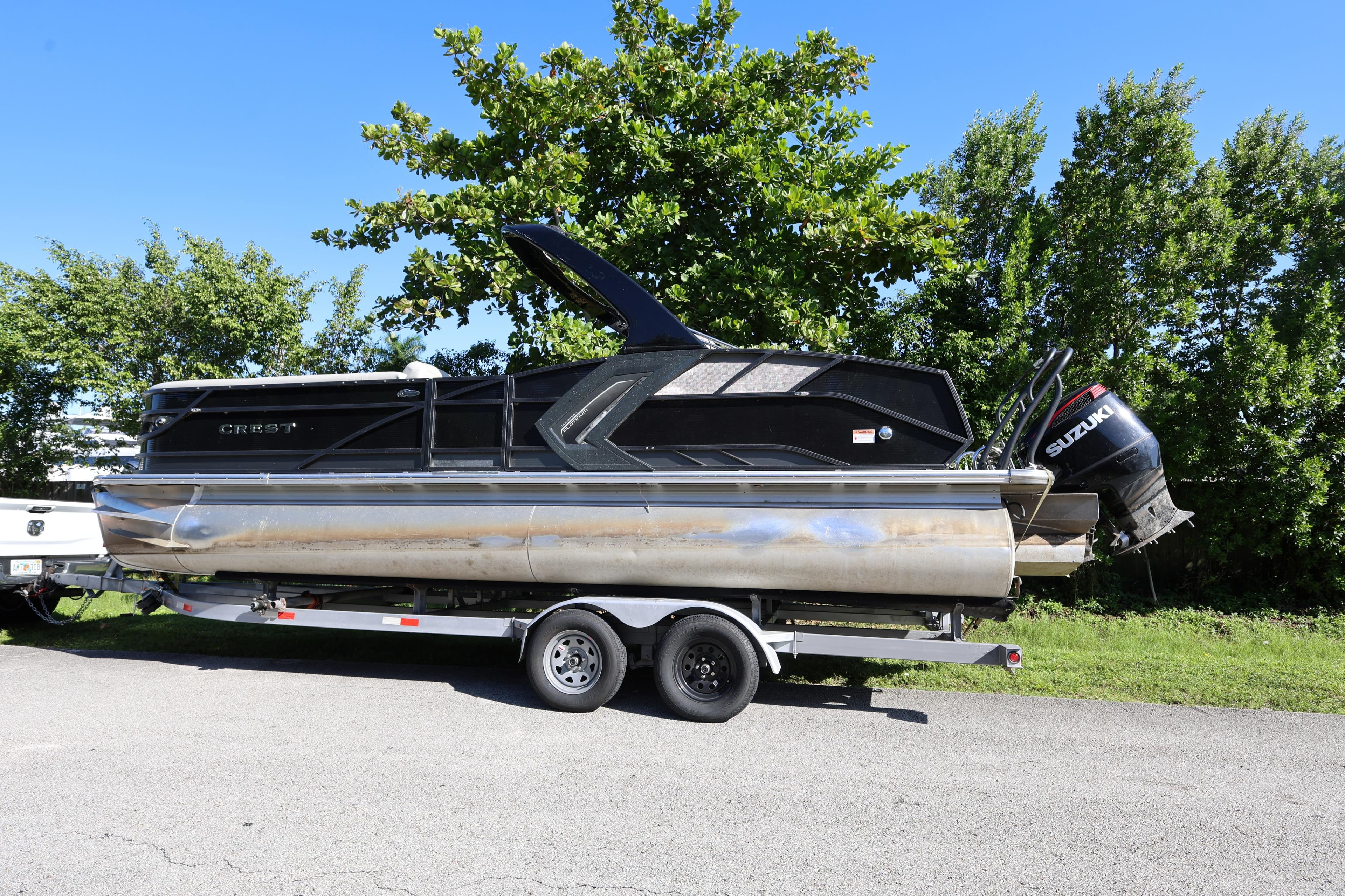 2022 Crest Caribbean Platinum 250SLRC pontoon boat on trailer, parked outdoors.