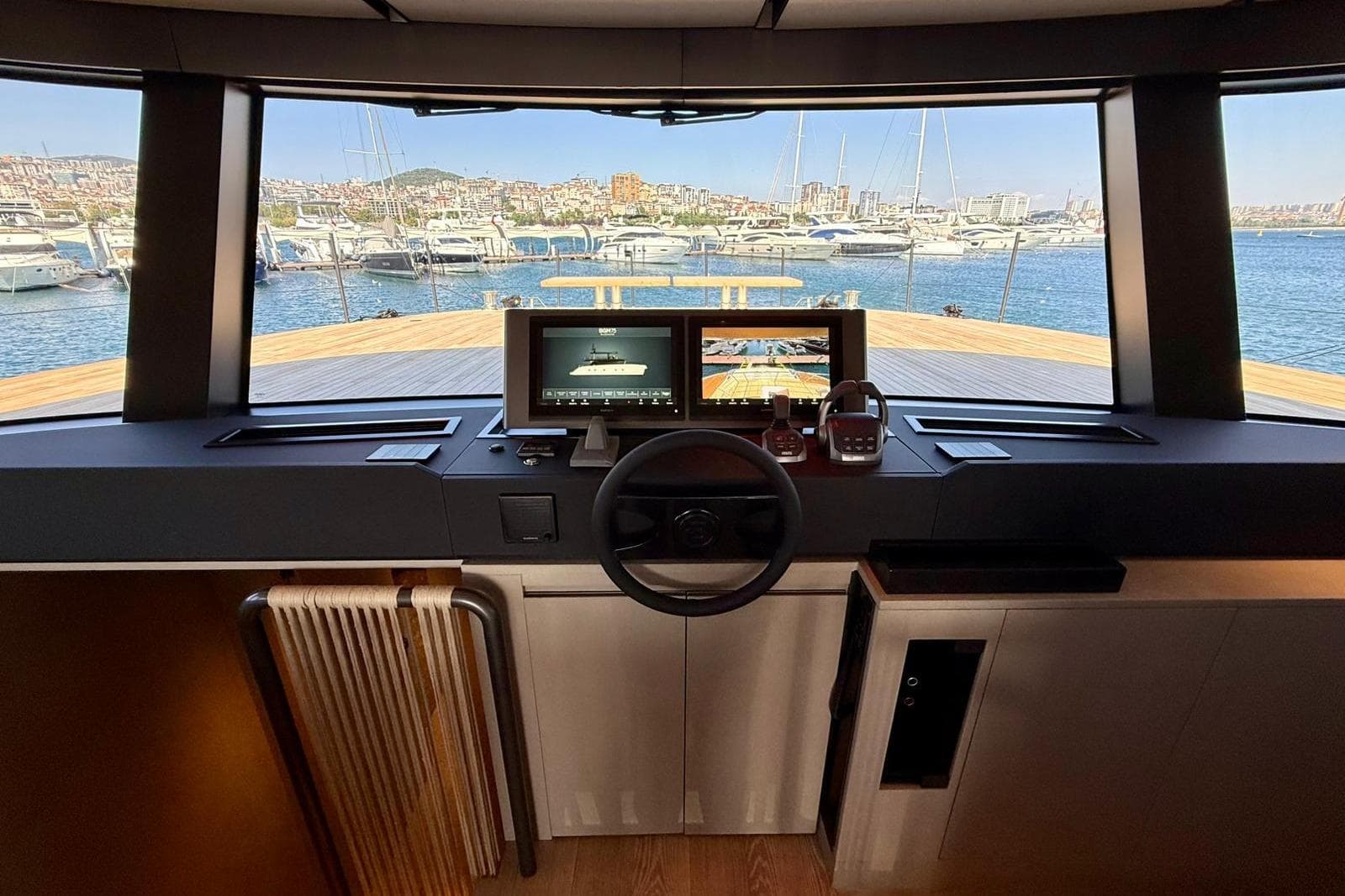 Interior helm view of 2025 Bluegame BGM75 yacht, featuring modern navigation equipment and marina backdrop.
