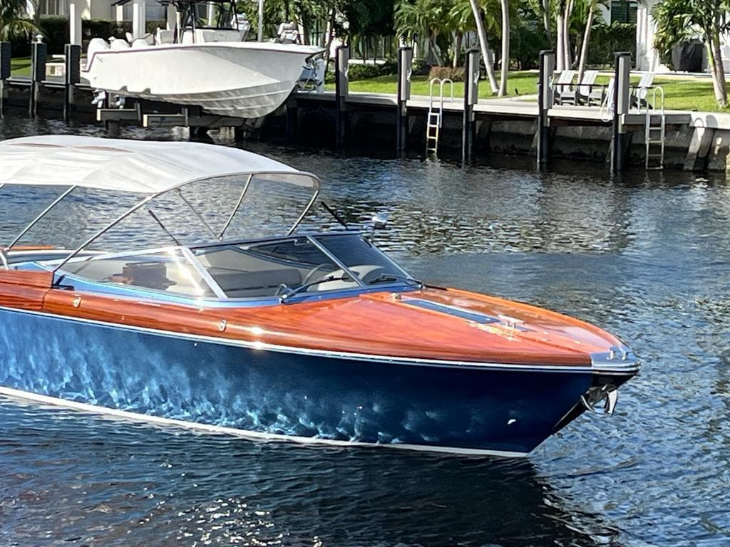 2012 Riva Aquariva Super boat with blue hull and wooden deck on a calm waterway.