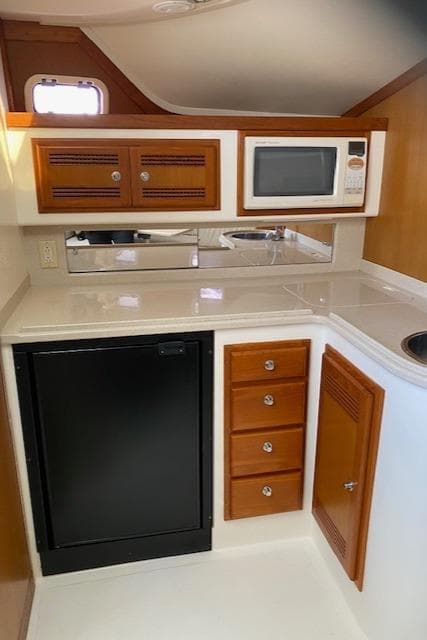 Compact kitchen area in a 2000 Cabo 35 Express boat with microwave and mini-fridge.