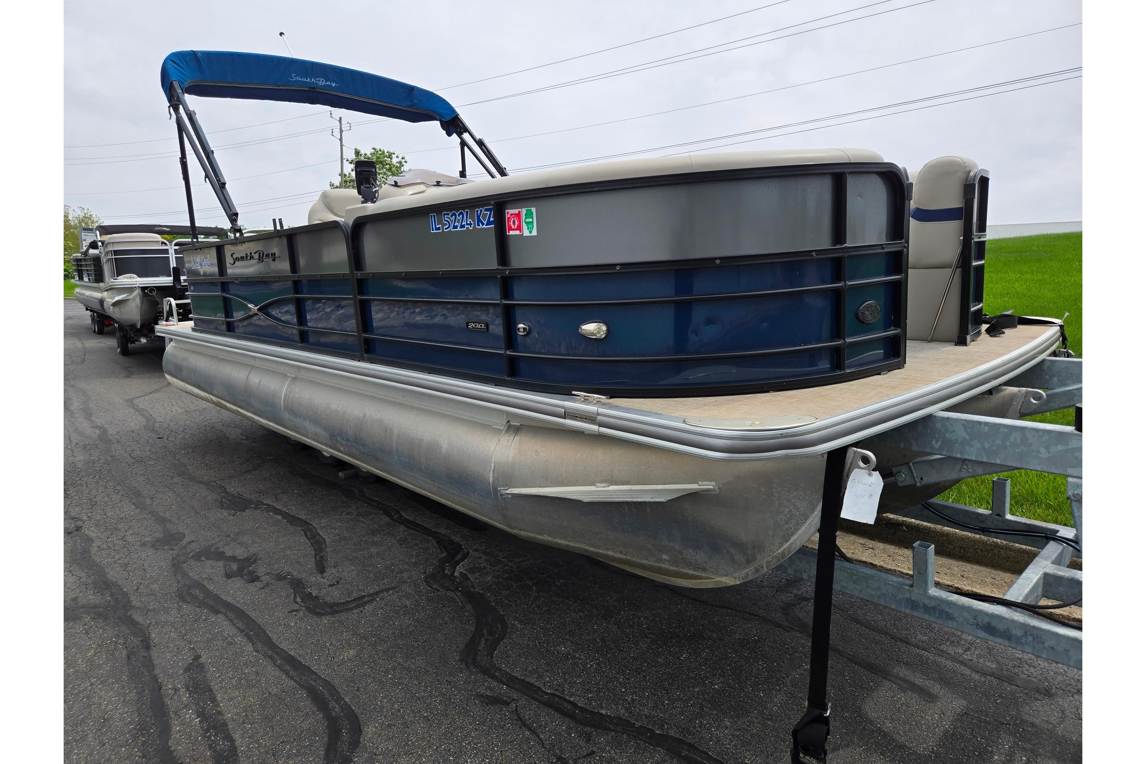 2019 South Bay S224FCR pontoon boat on trailer, blue canopy, parked on asphalt.