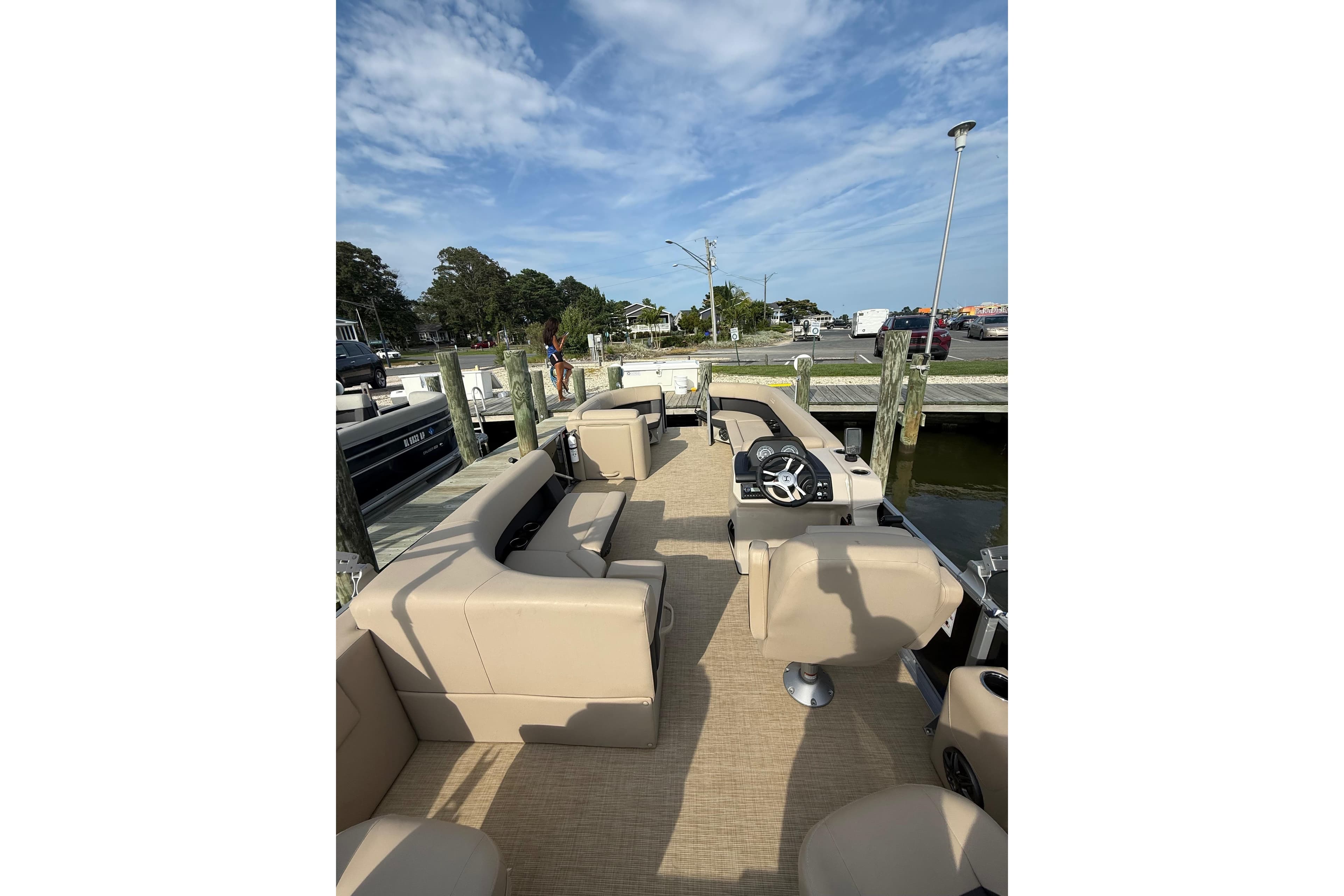2025 Harris Cruiser 230 pontoon boat with beige seating at a dock under blue skies.