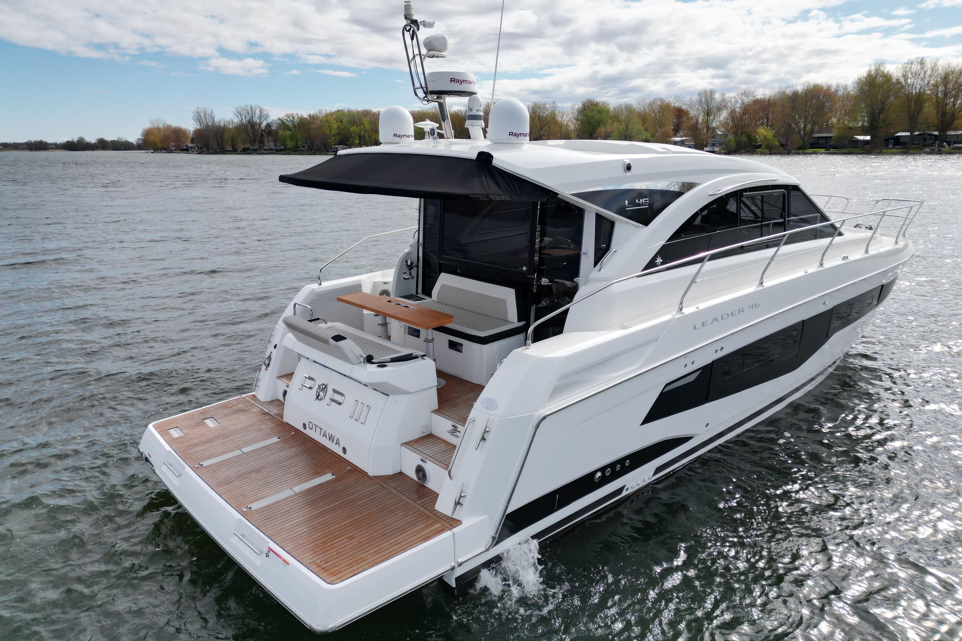 2022 Jeanneau Leader 46 yacht cruising on a calm lake under a partly cloudy sky.