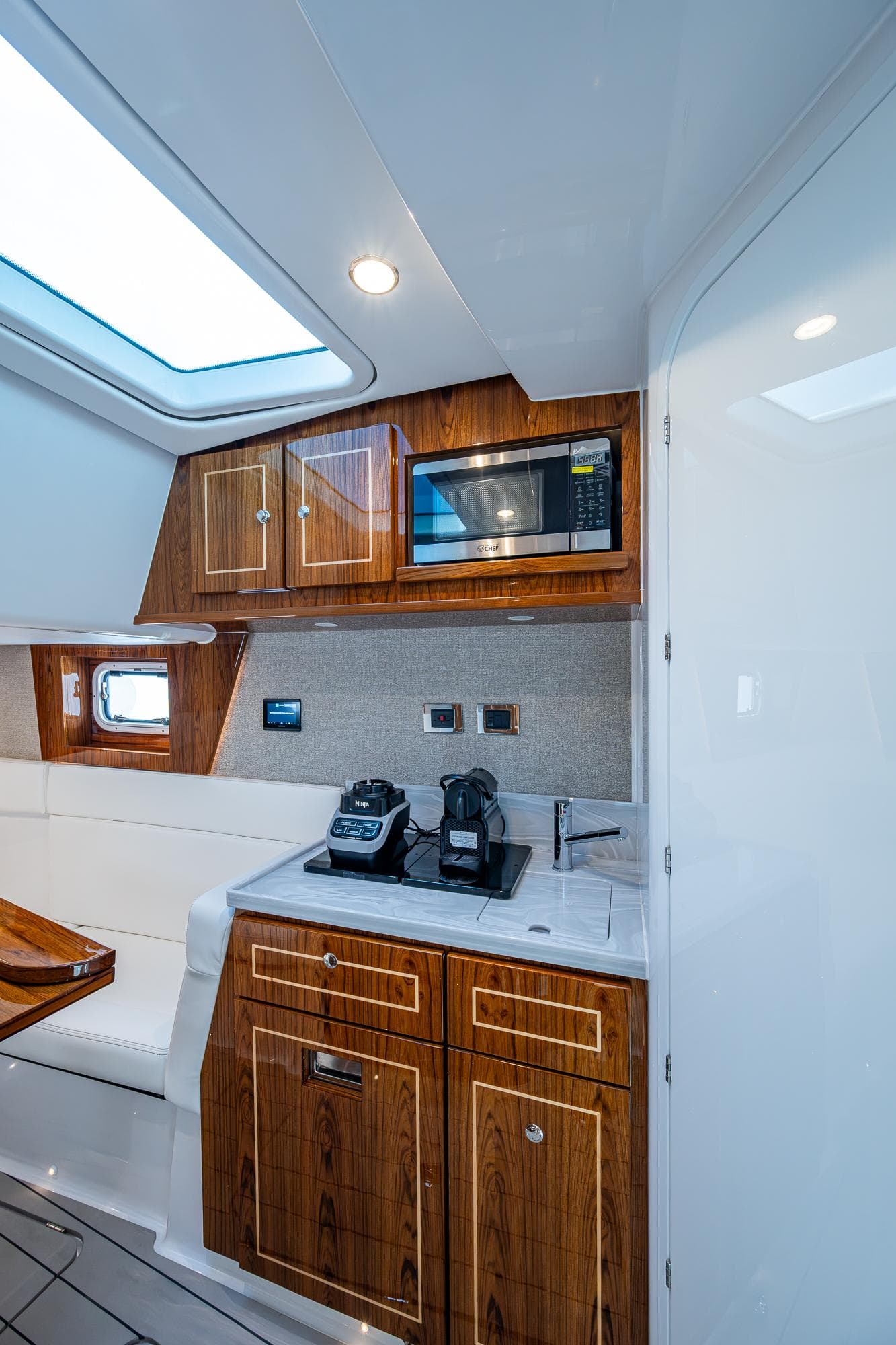 Interior of 2025 HCB 48 Campeon yacht with modern kitchenette and wooden cabinetry.