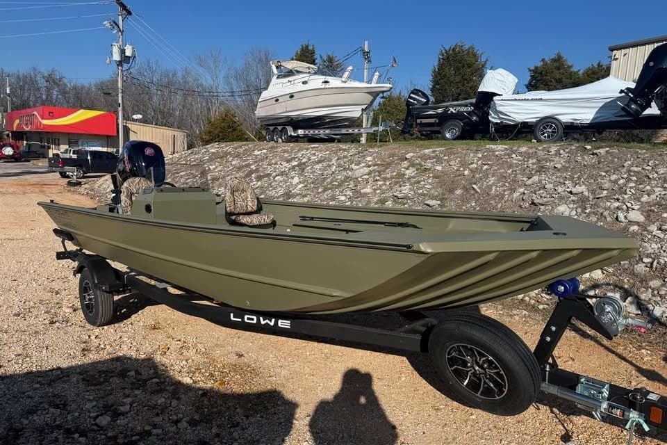 2026 Lowe Roughneck 2070 boat on trailer, parked outdoors under clear blue sky.