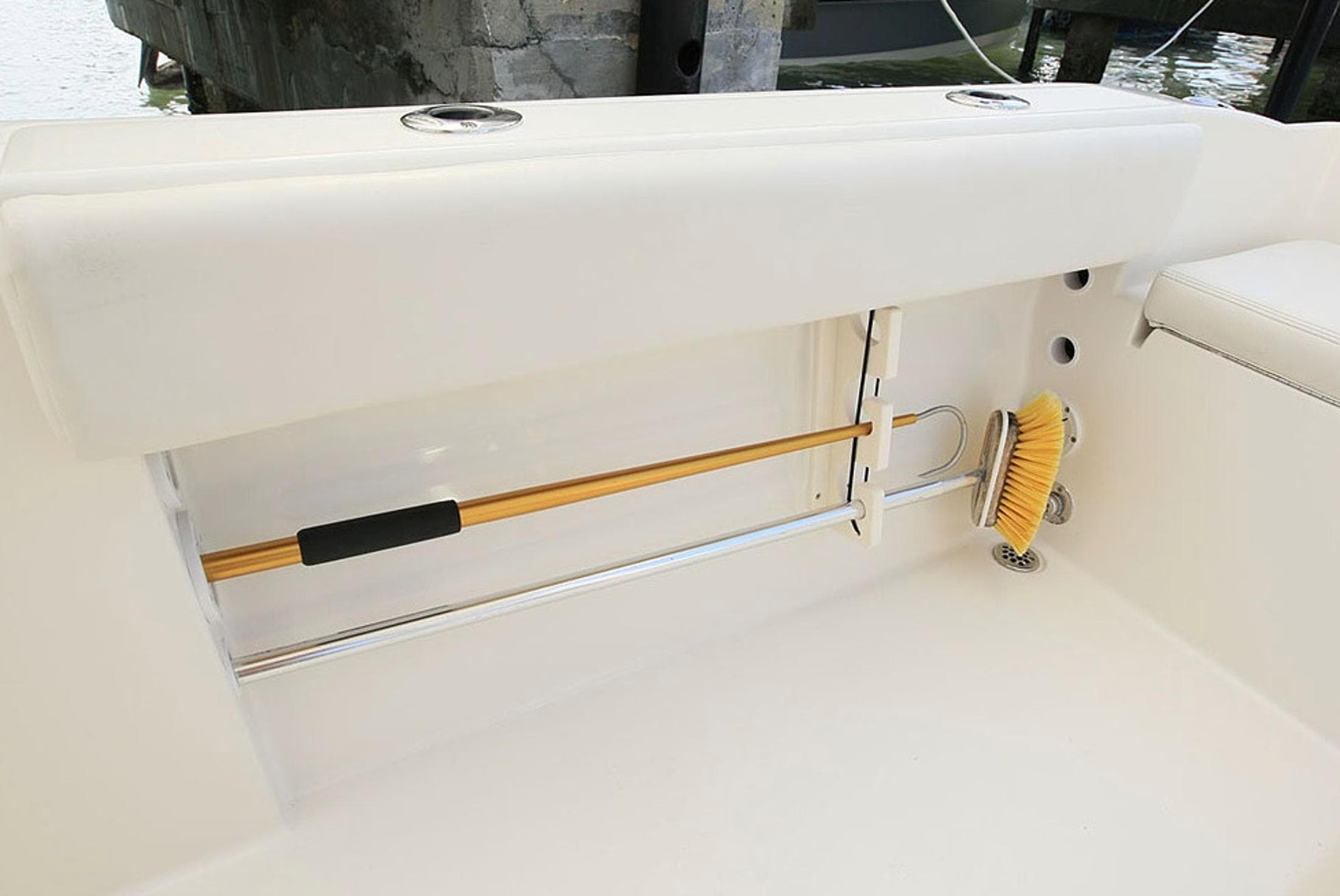 Manufacturer Provided Image: 2014 Cobia 217 Center Console boat storage compartment with cleaning brush and rod holder.
