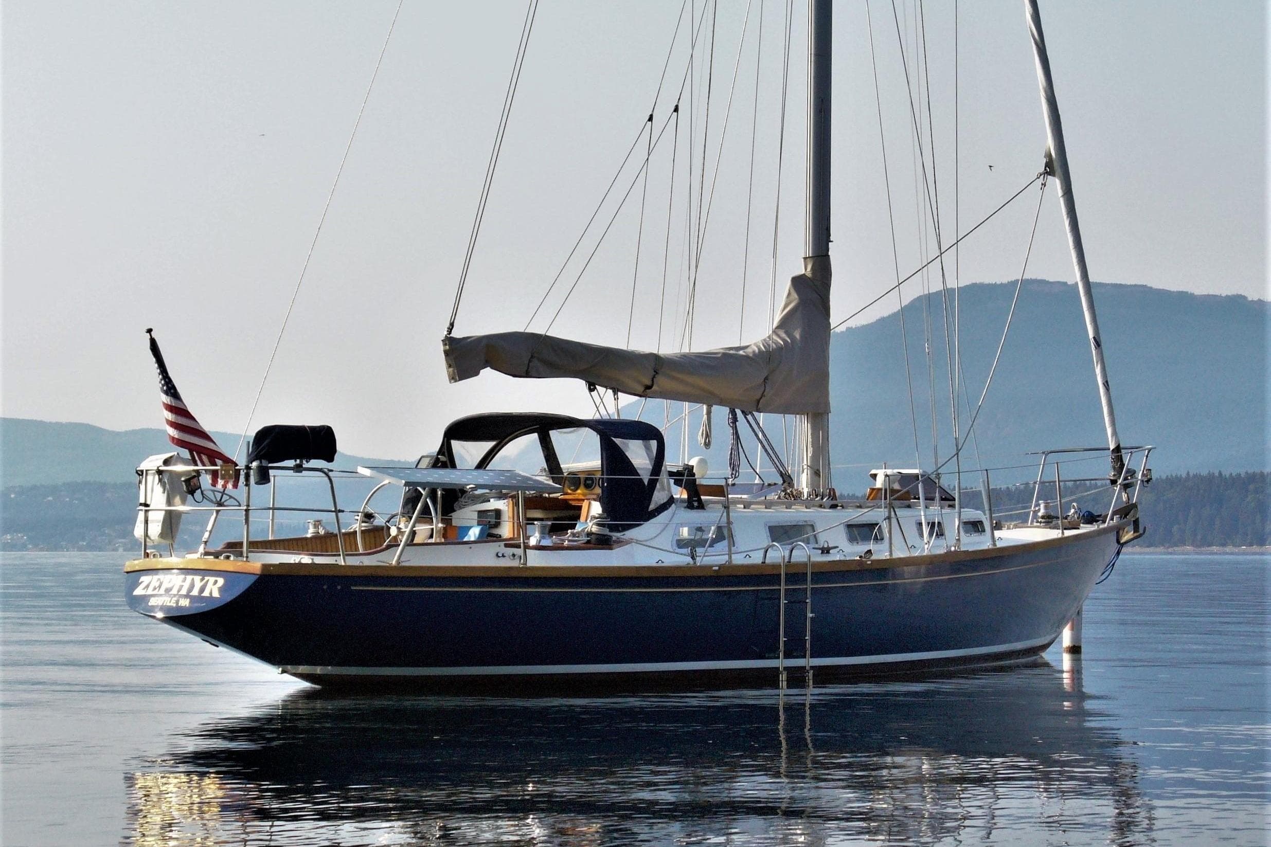 Sailboat Ohlson 38, 1984 model, anchored on calm water with mountainous backdrop.