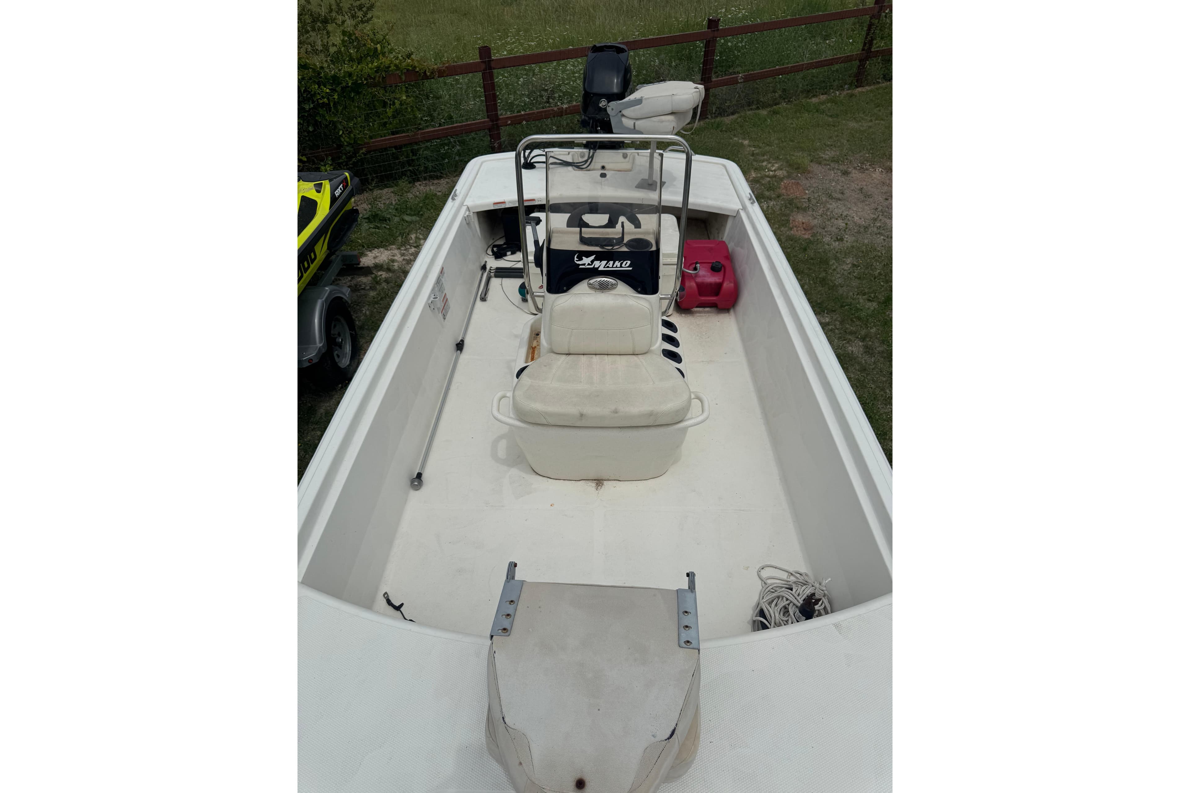 2013 Mako Pro Skiff 17 CC boat with seating and storage, parked on grass.