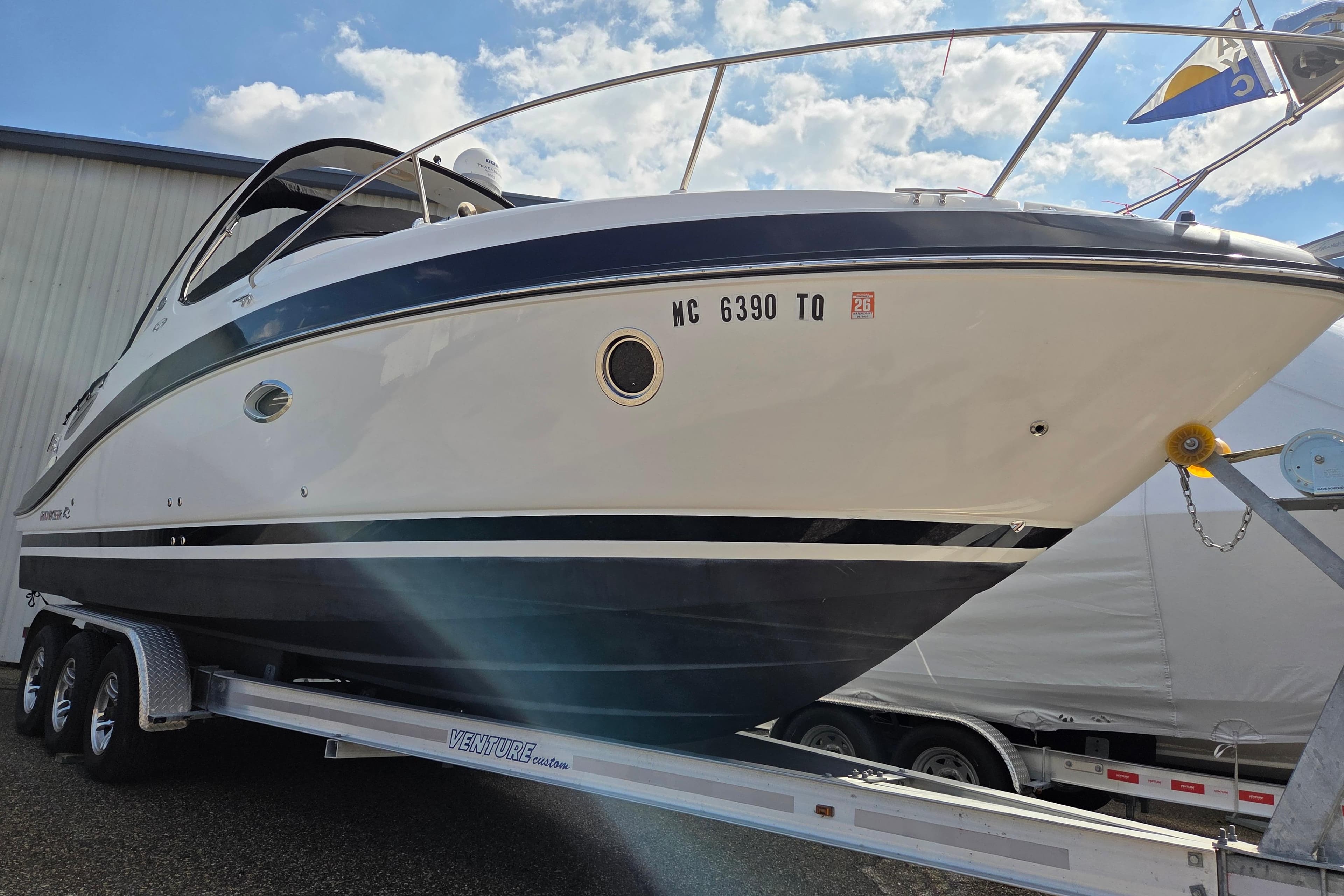2014 Rinker 290 Express Cruiser on trailer under blue sky.