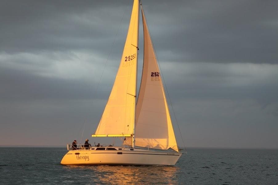Sailing yacht Hunter Legend 37.5, 1991 model, gliding on calm waters at sunset.
