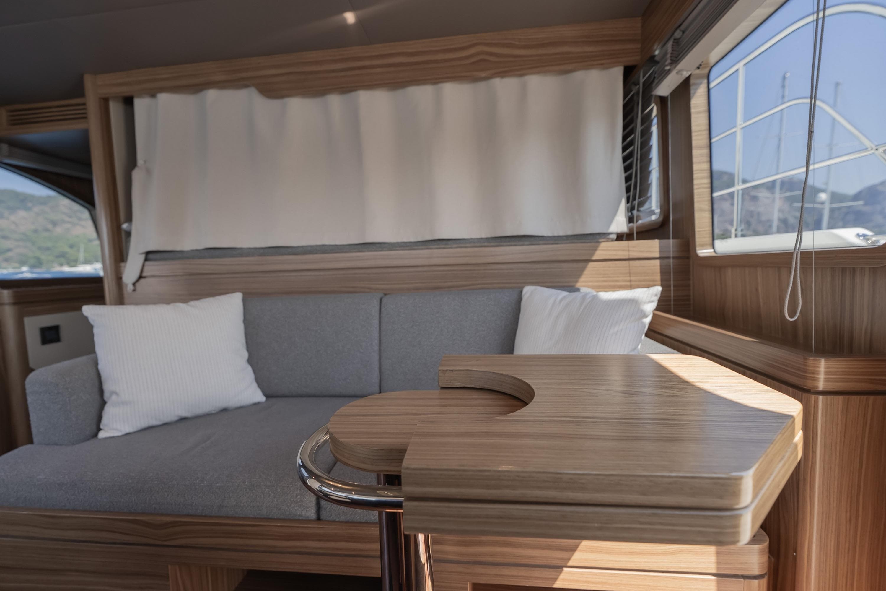 Interior of 2024 Nordhavn 51 yacht with wooden table and gray sofa.