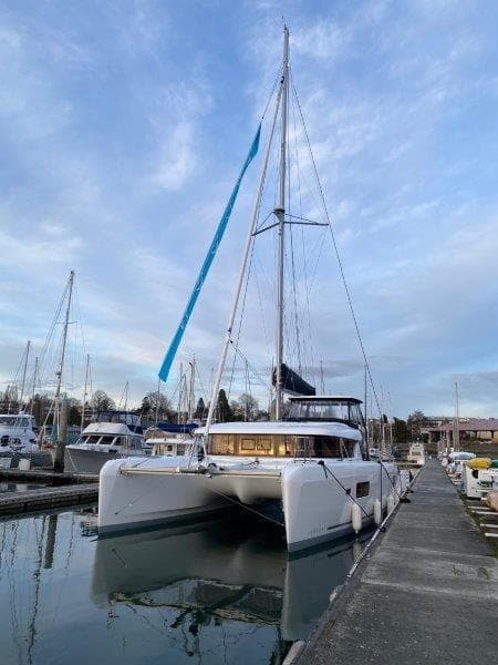 2024 Lagoon 42 catamaran docked at a marina under a blue sky.
