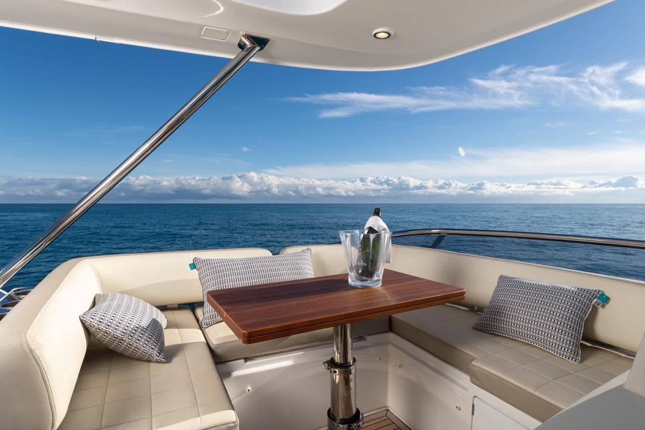 Luxurious 2016 Azimut 66 yacht deck with ocean view, featuring elegant seating and a wooden table.