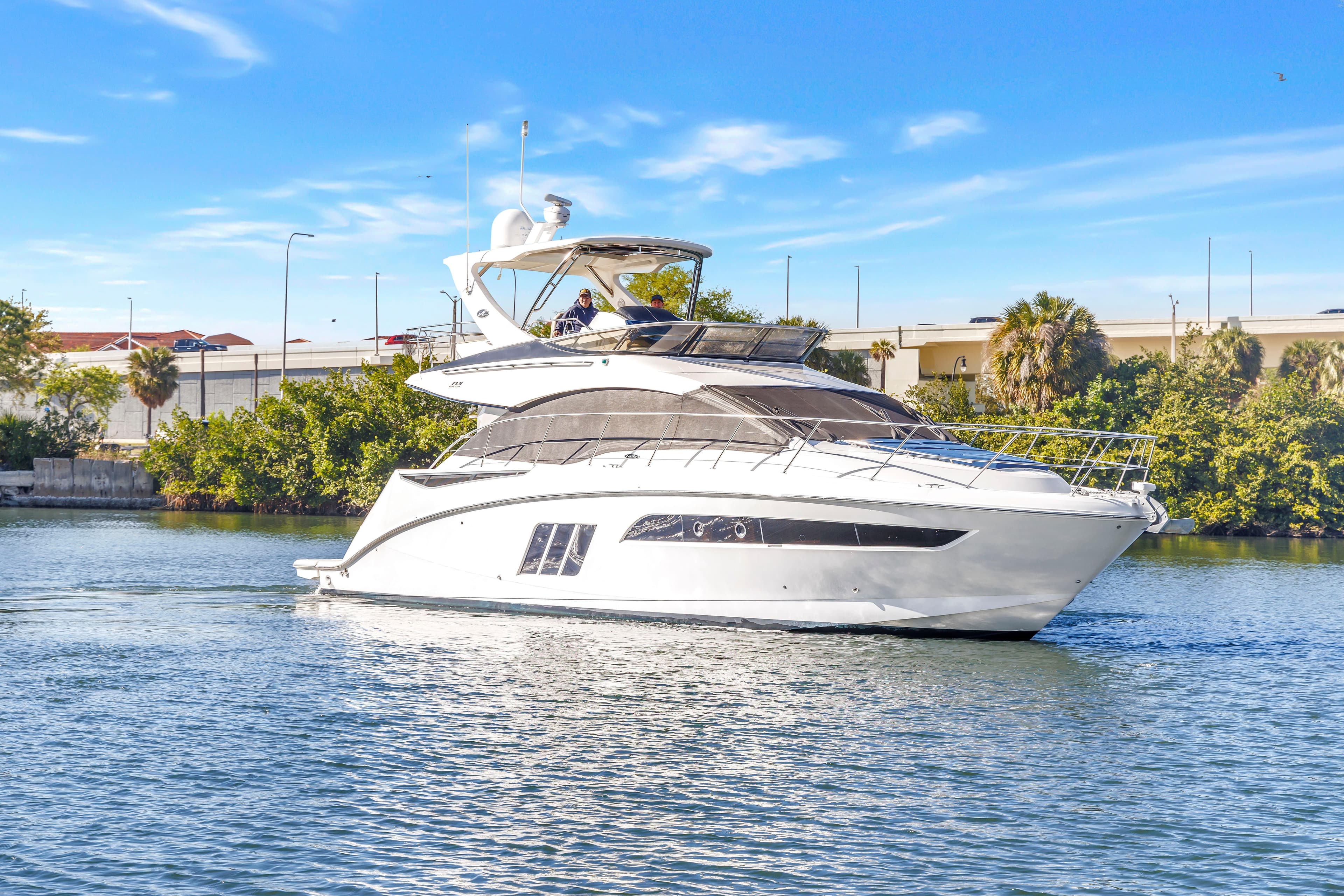 2016 Sea Ray 510 Fly yacht cruising on a sunny day, surrounded by greenery.