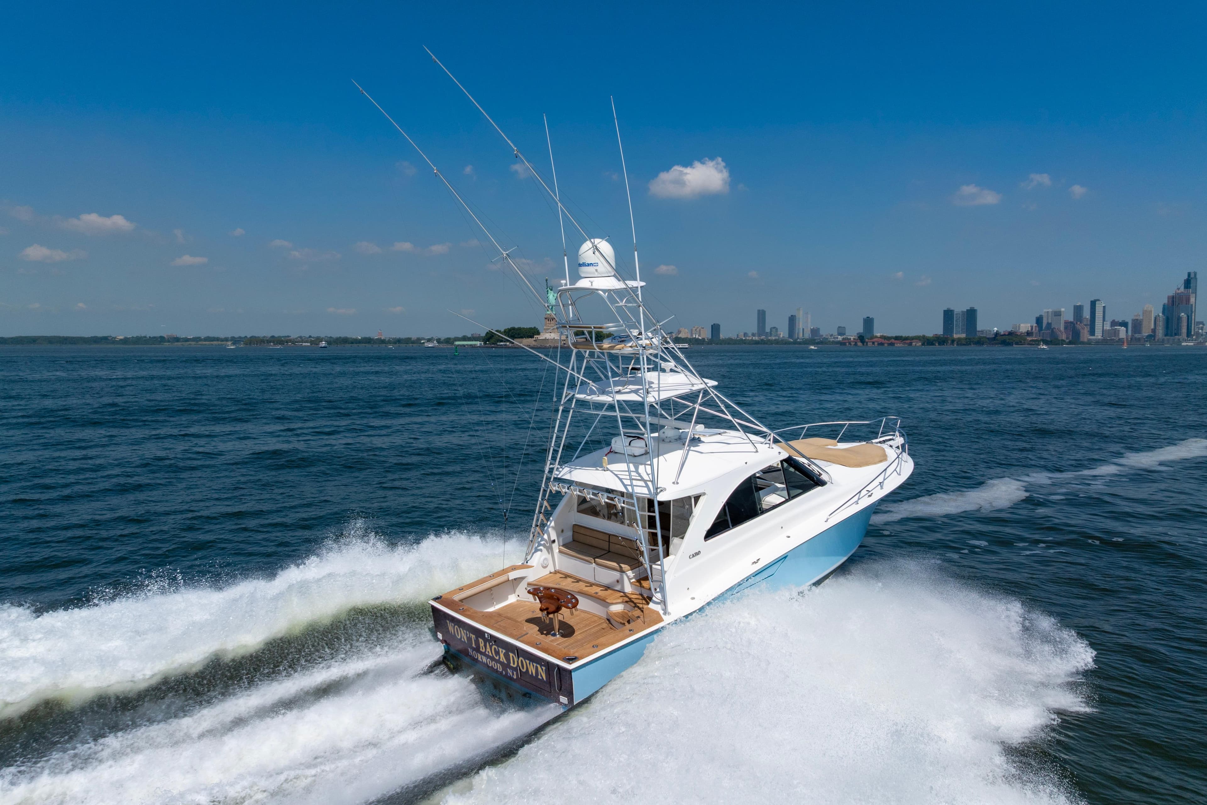 2012 Cabo 44 Hardtop Express yacht cruising near city skyline on a sunny day.