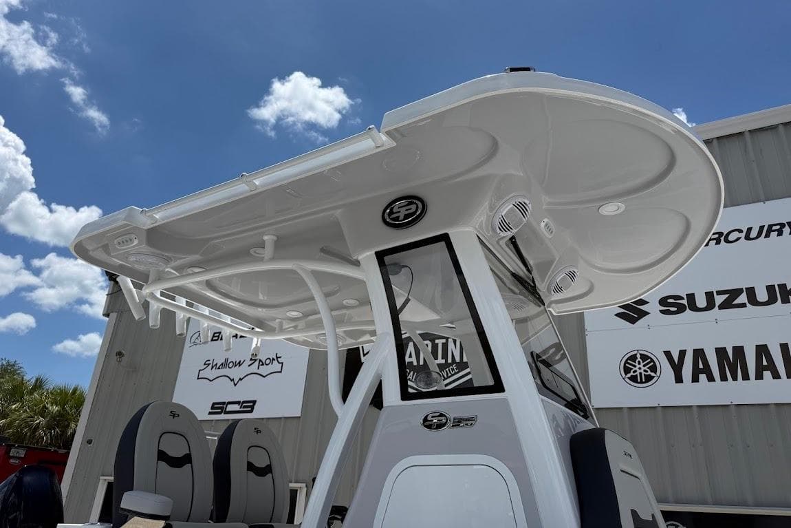 2026 Sea Pro 262 Offshore boat with T-top, parked near dealership signs under blue sky.