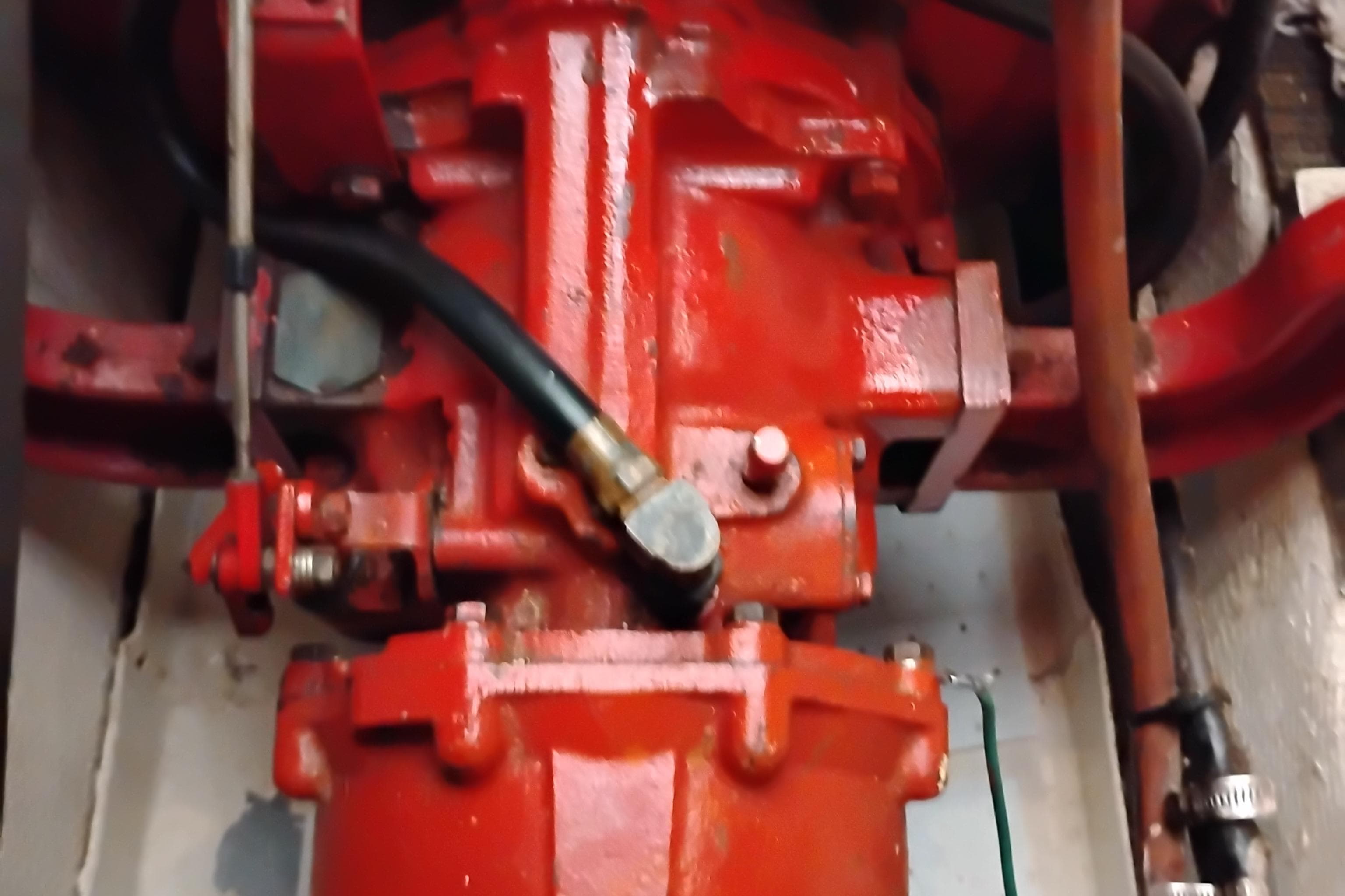 Engine component of 1978 Puget 38 Europa Trawler, featuring red mechanical parts and hoses.