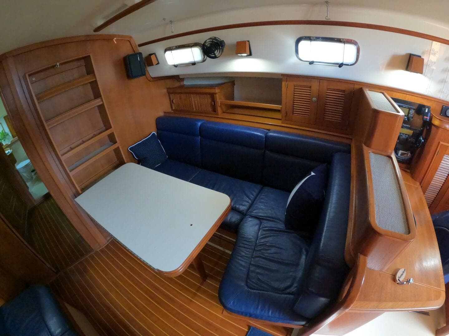 Interior of 1999 Island Packet 45 sailboat with blue seating and wooden cabinetry.