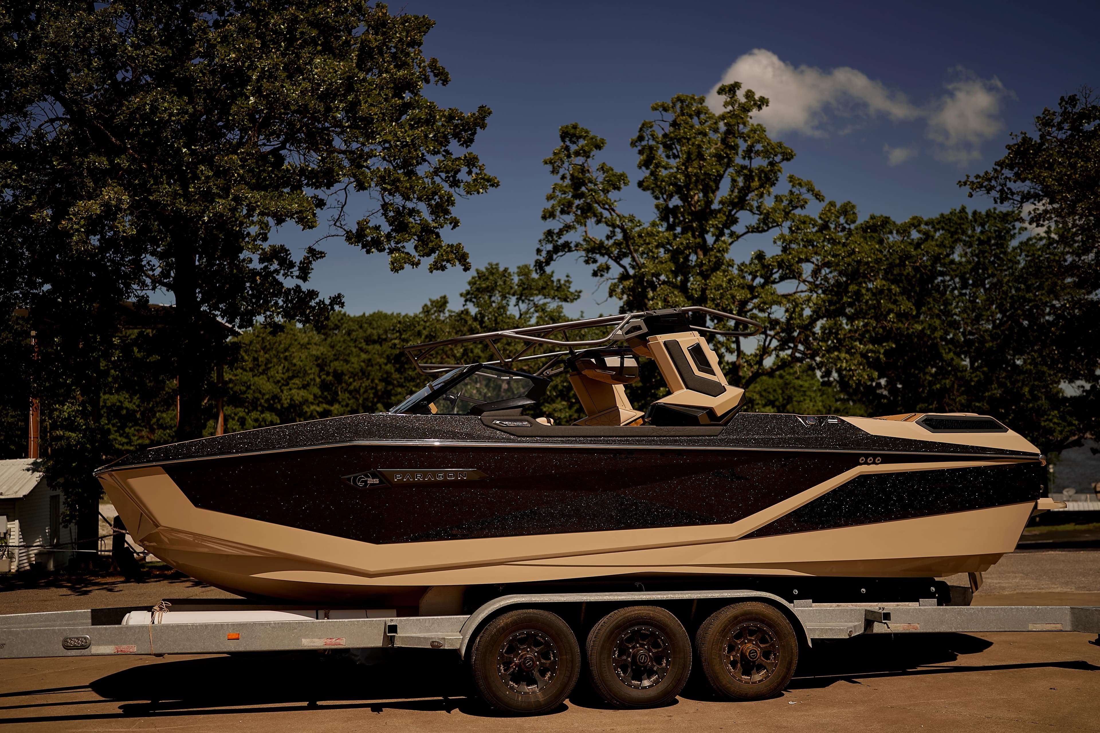 2025 Nautique Super Air Nautique G25 Paragon boat on trailer, surrounded by trees.