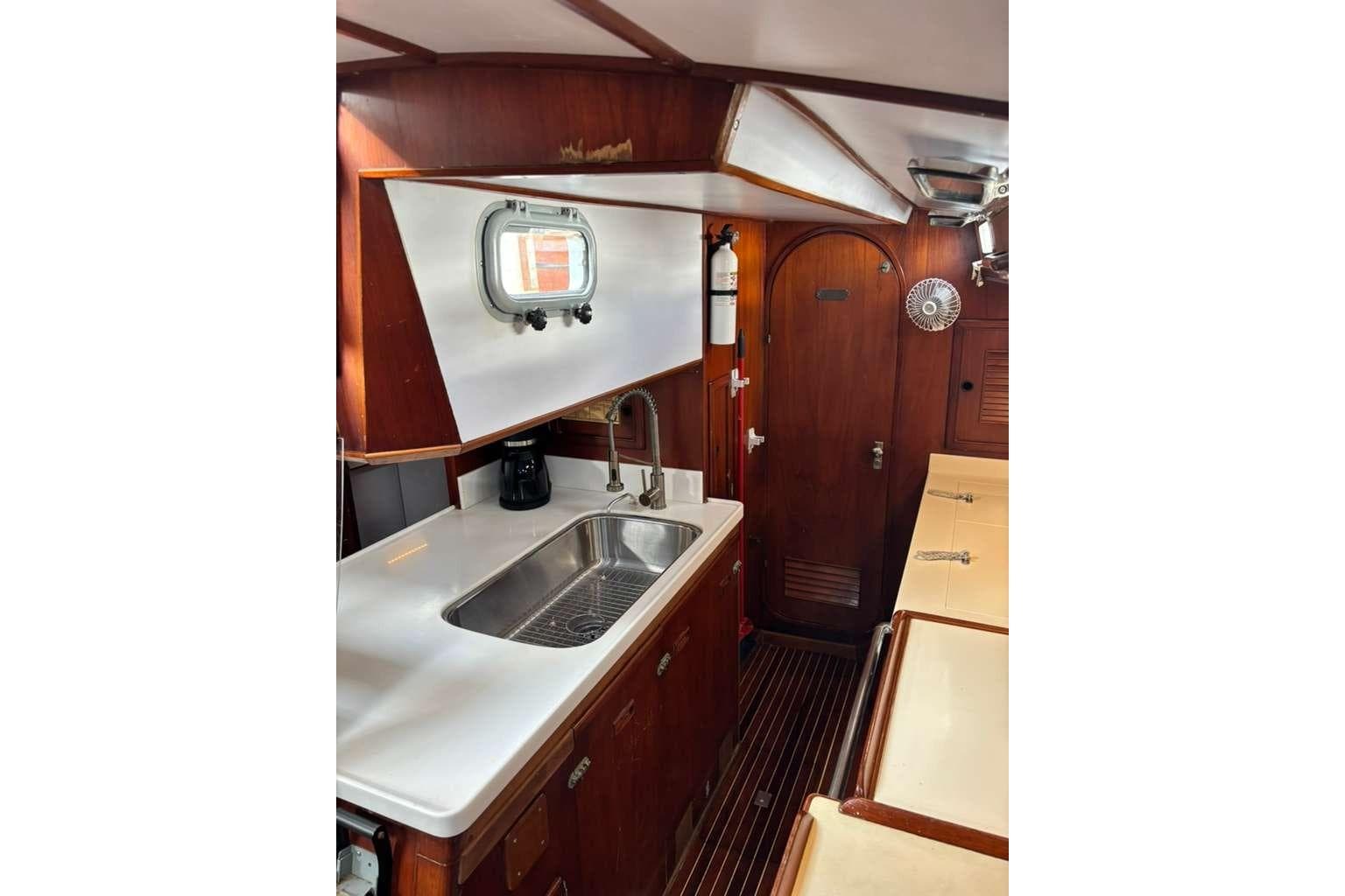 1982 Stevens 47 yacht interior with wooden cabinetry, sink, and porthole window.