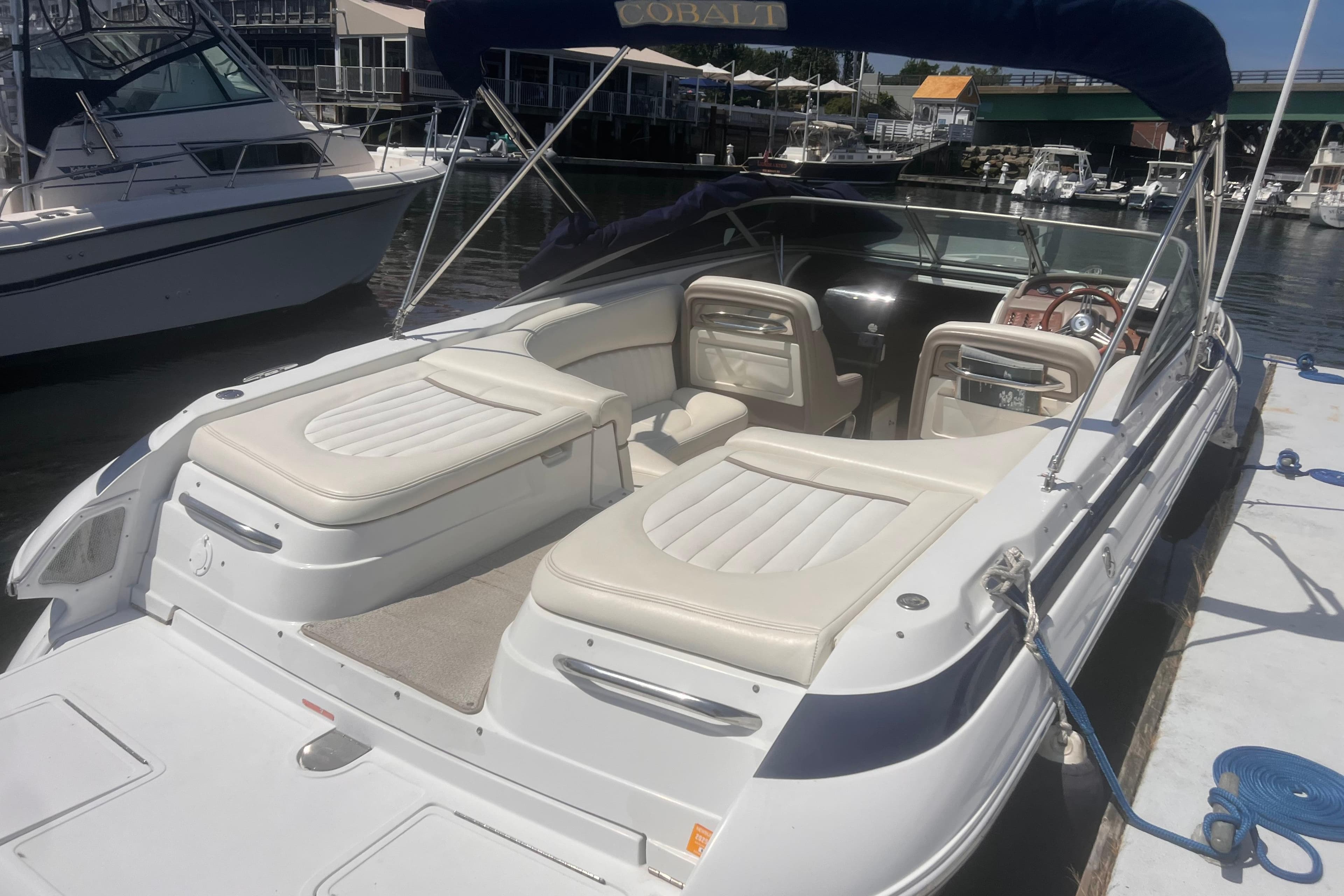 2003 Cobalt 263 boat docked, featuring white seating and a blue canopy.