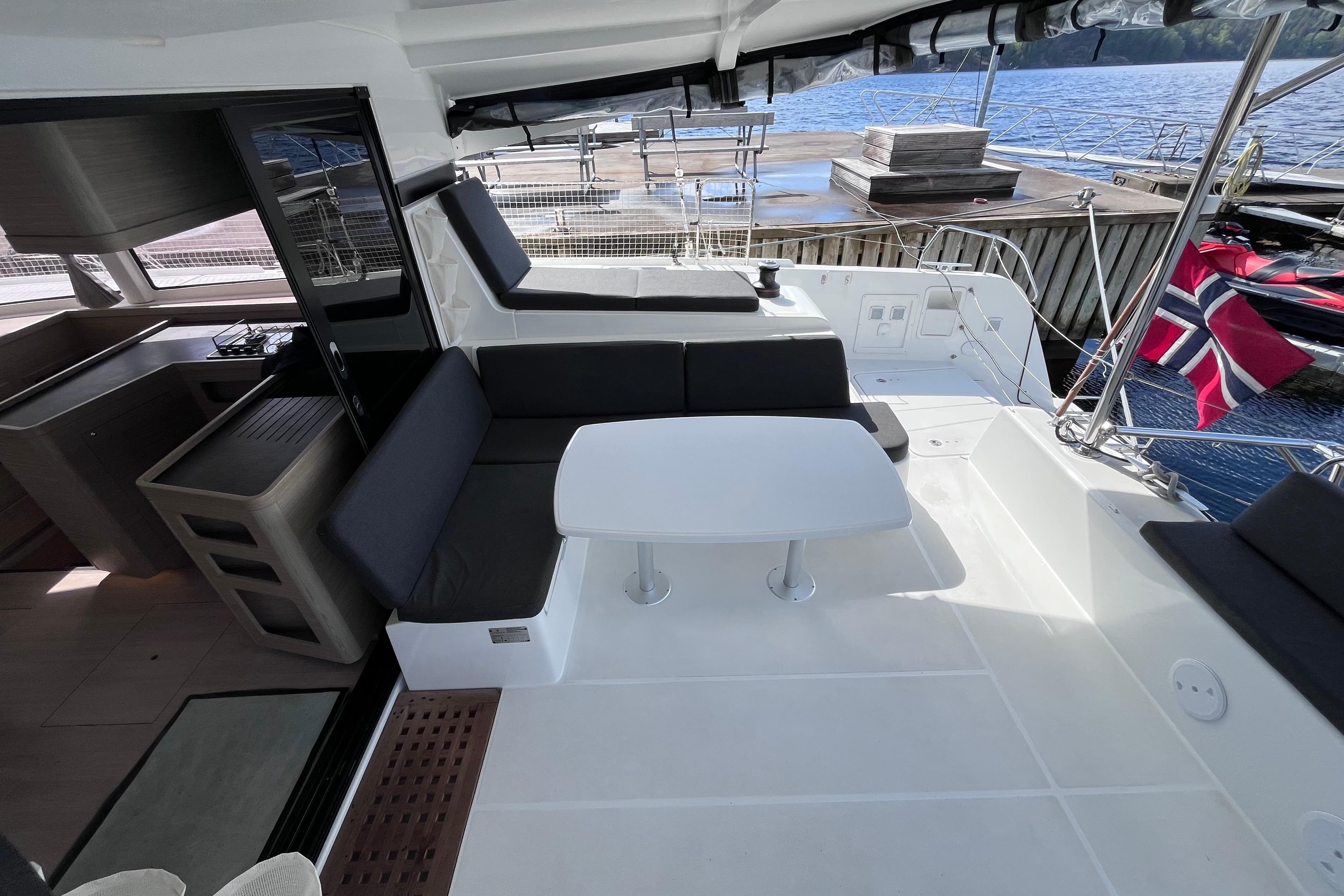 Luxurious 2024 Lagoon 42 yacht interior with seating area and table, docked by the water.