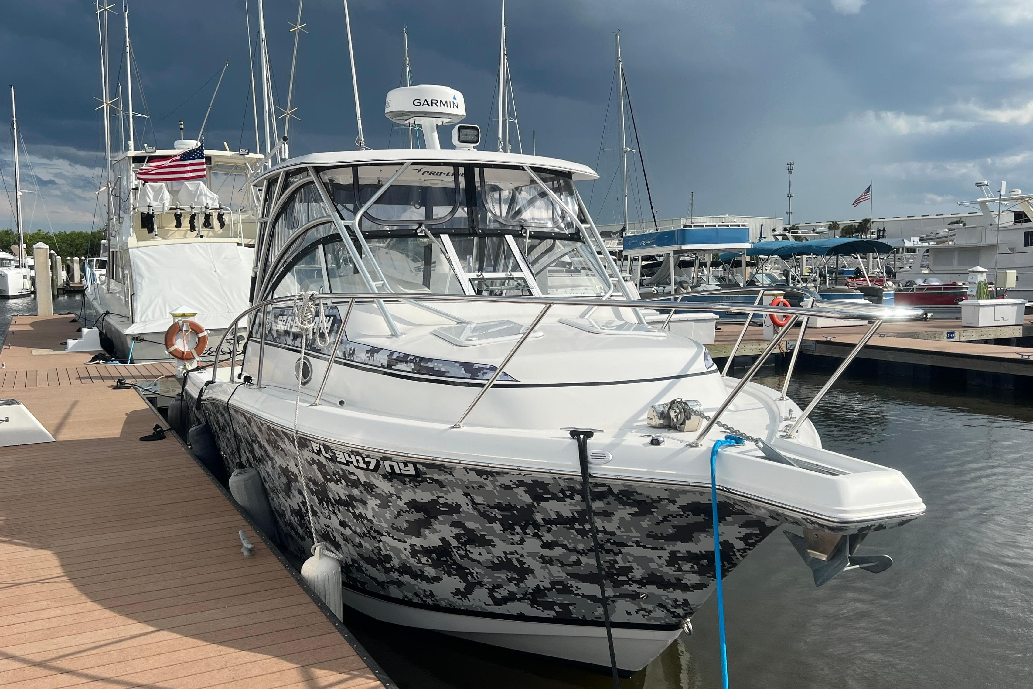 2008 Pro-Line 32 Express boat docked at marina, featuring camouflage design and Garmin equipment.