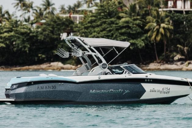 2018 MasterCraft XStar boat on tropical water with lush greenery background.