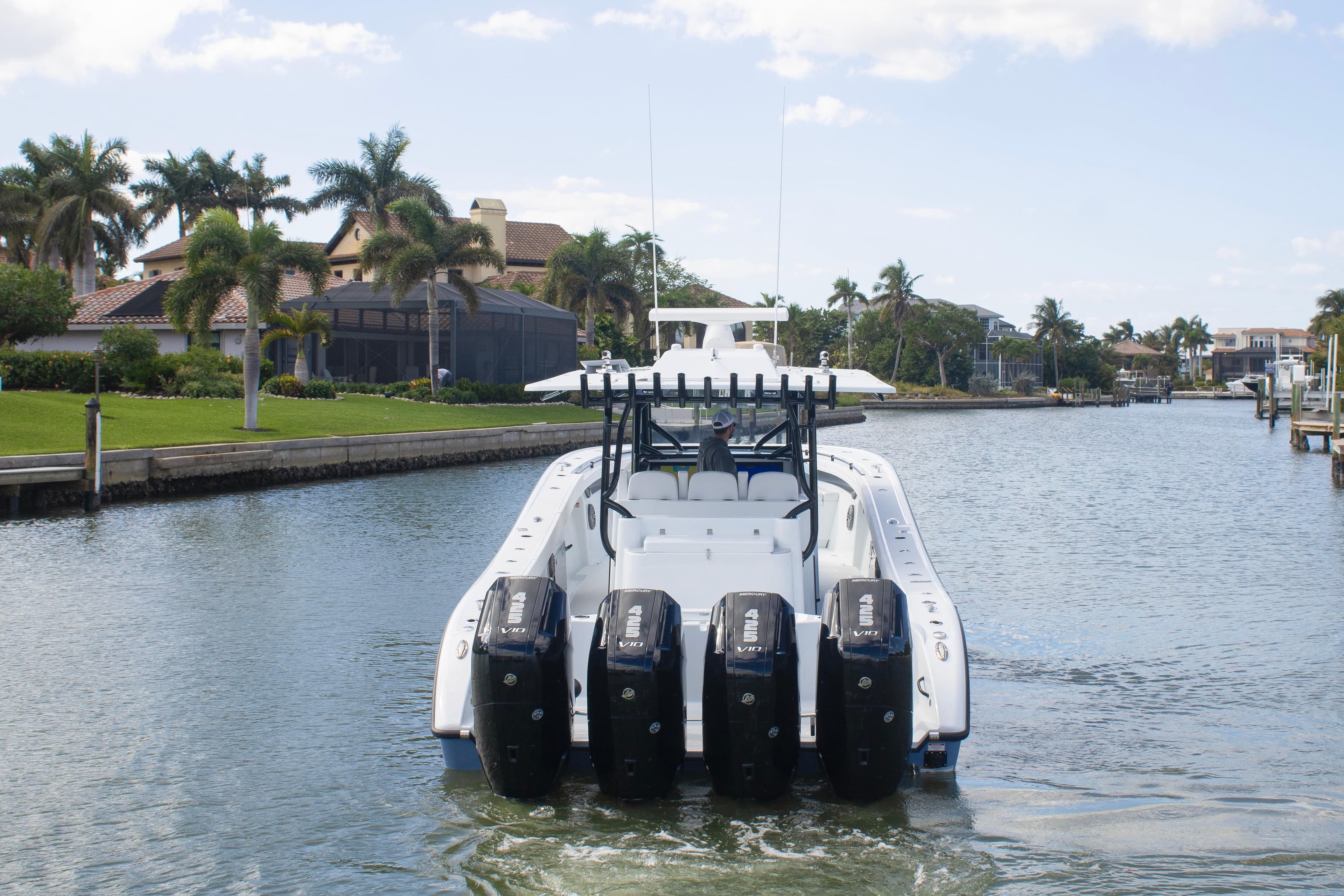 2026 Yellowfin 42 Offshore boat with four engines cruising in a scenic canal.