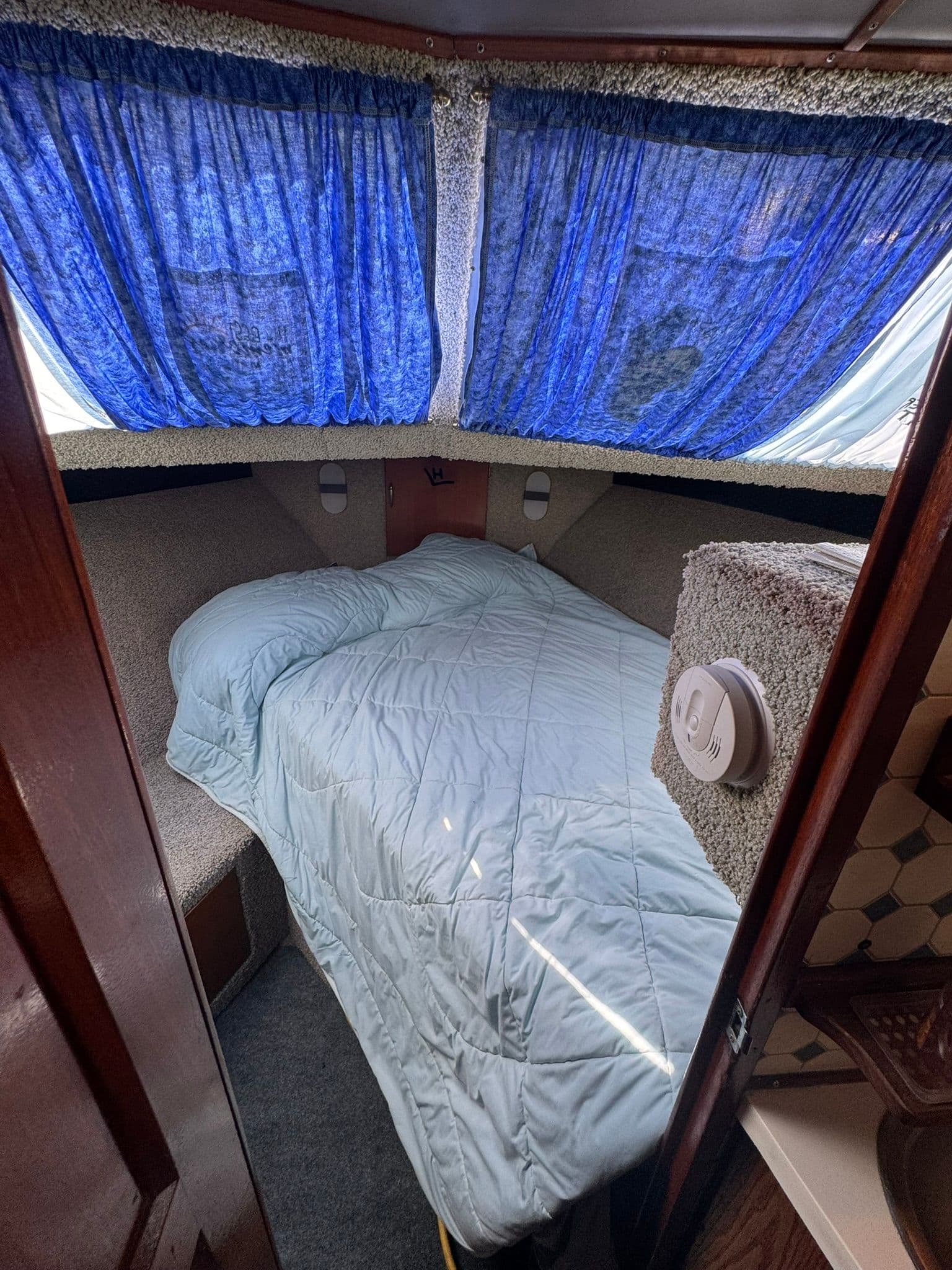 Interior of 1968 Hatteras 31 Flybridge with bed and blue curtains.