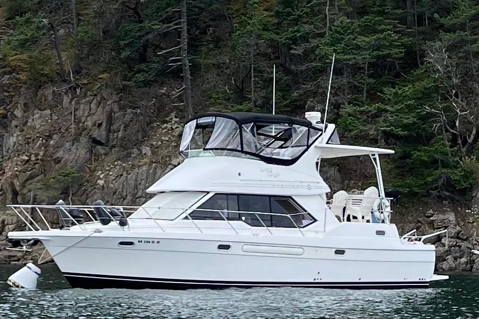 1996 Bayliner 4087 Aft Cabin Motoryacht on water near rocky shoreline.